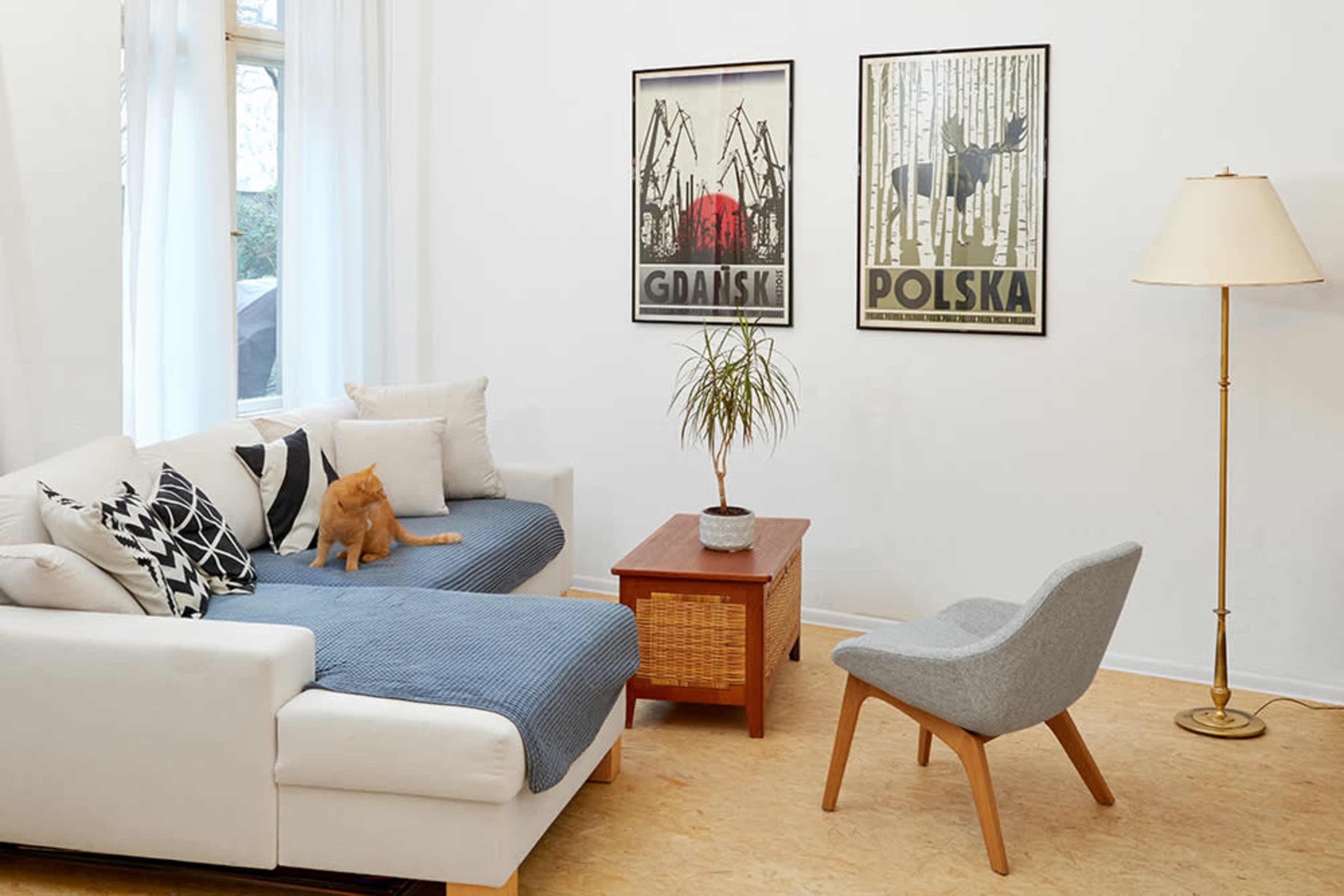 A cozy living room features a white sofa, a wooden coffee table, a comfortable chair, and decorative posters on the wall.