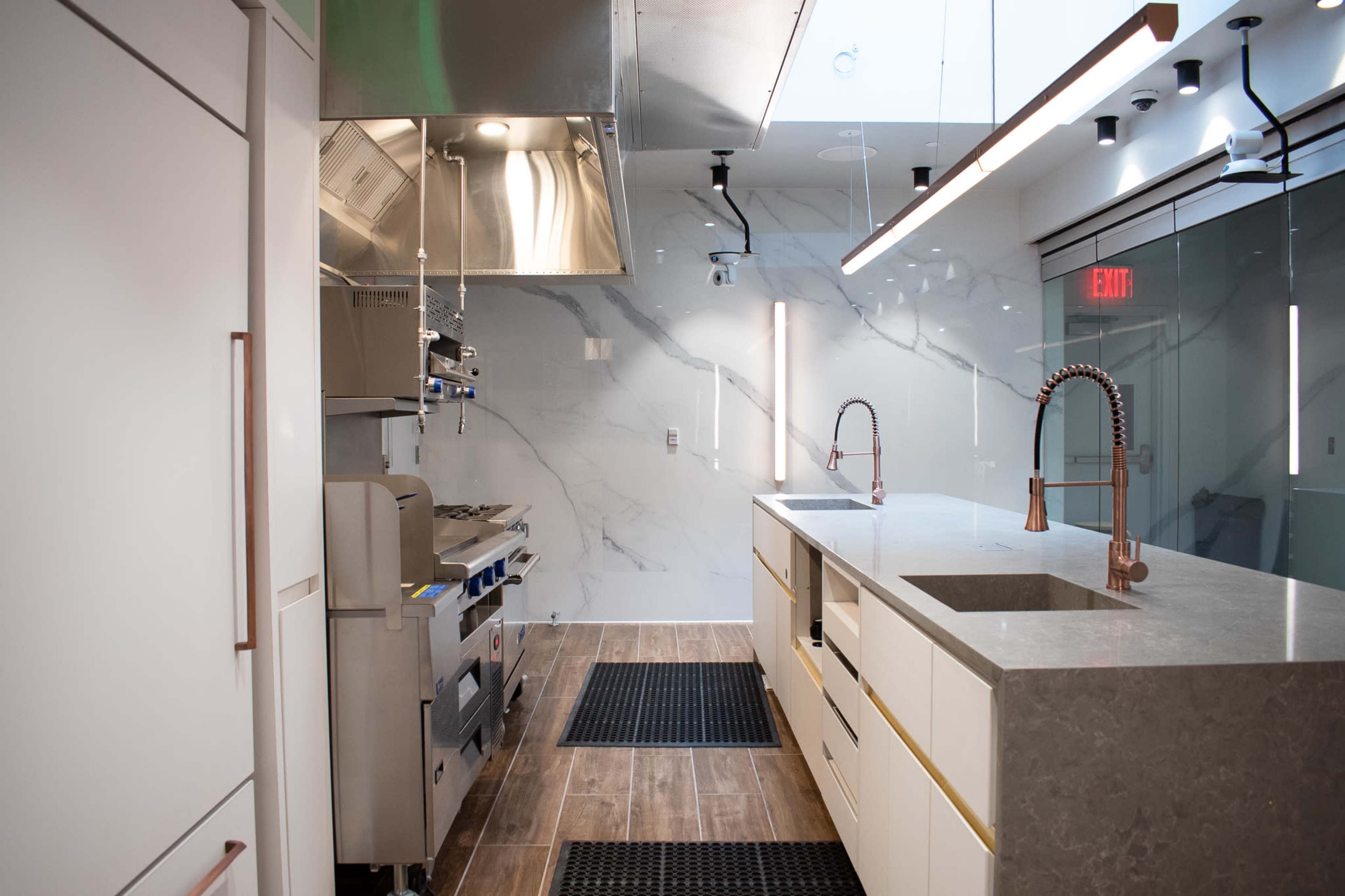 A modern kitchen with stainless steel appliances, a large gray countertop, and sleek cabinetry.