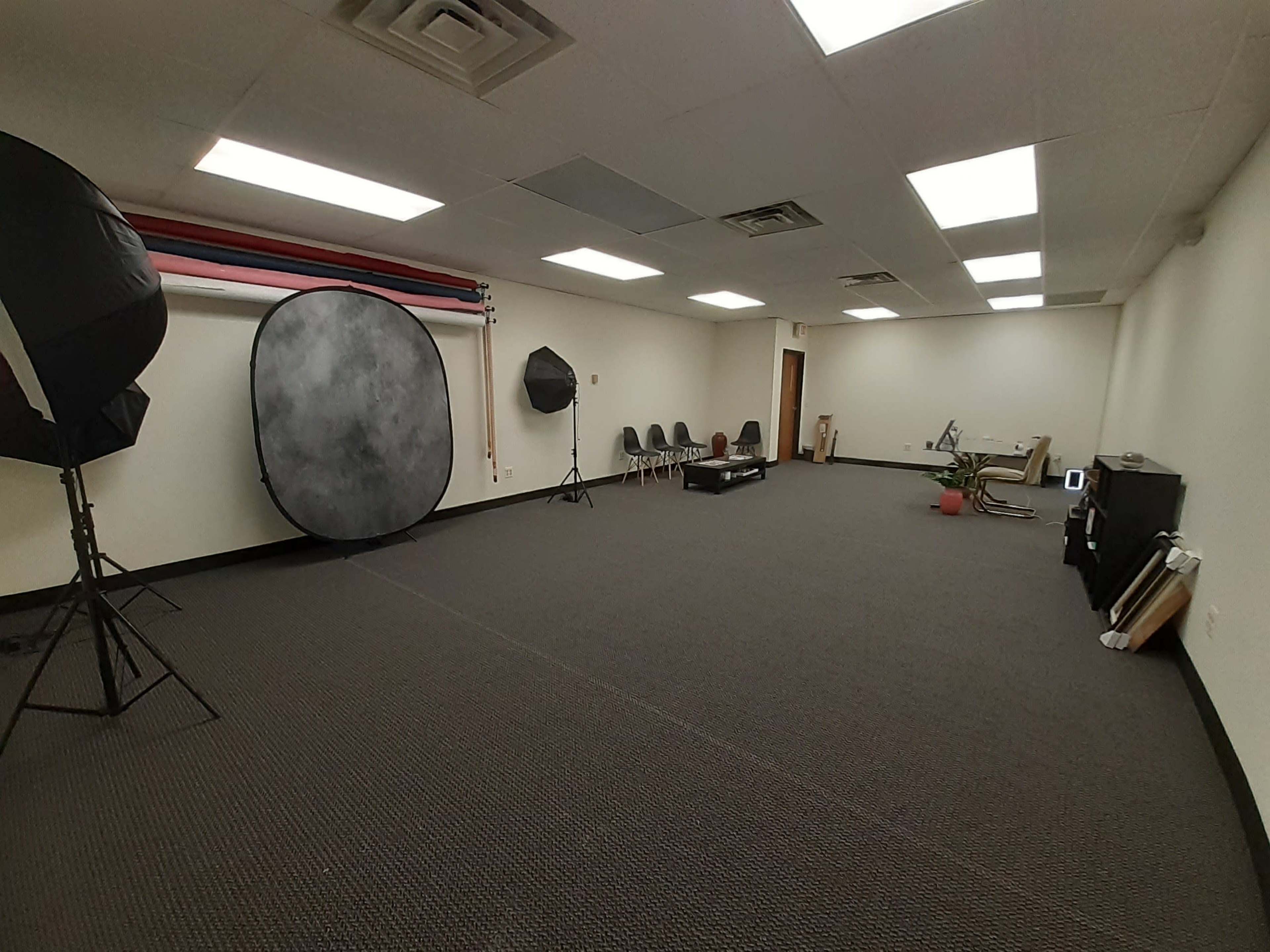 A spacious, empty studio room equipped with photography backdrops and lighting equipment.