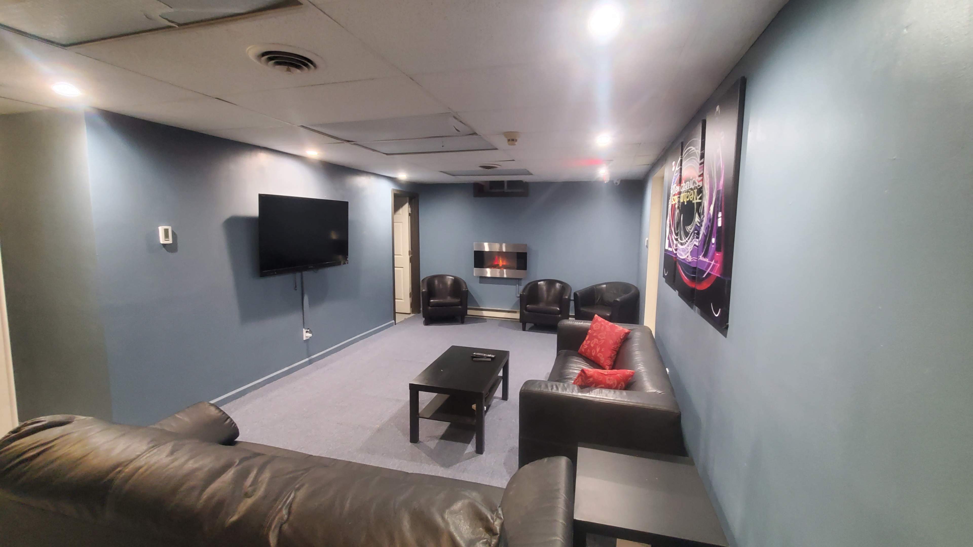 A living room with a television, a modern fireplace, leather sofas, and a coffee table against blue walls.