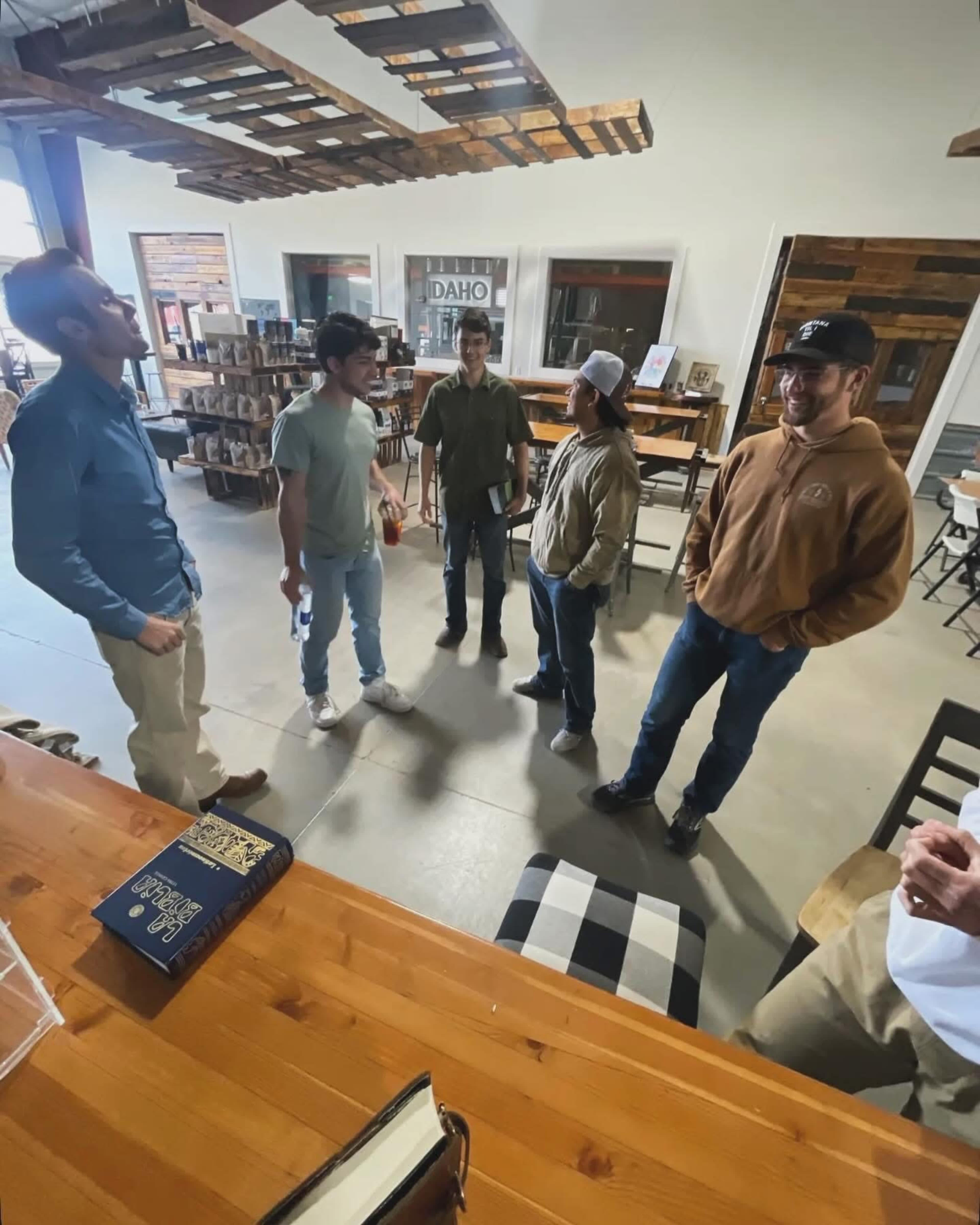 A group of five people stands in a spacious, well-lit room featuring wooden furniture and decor.