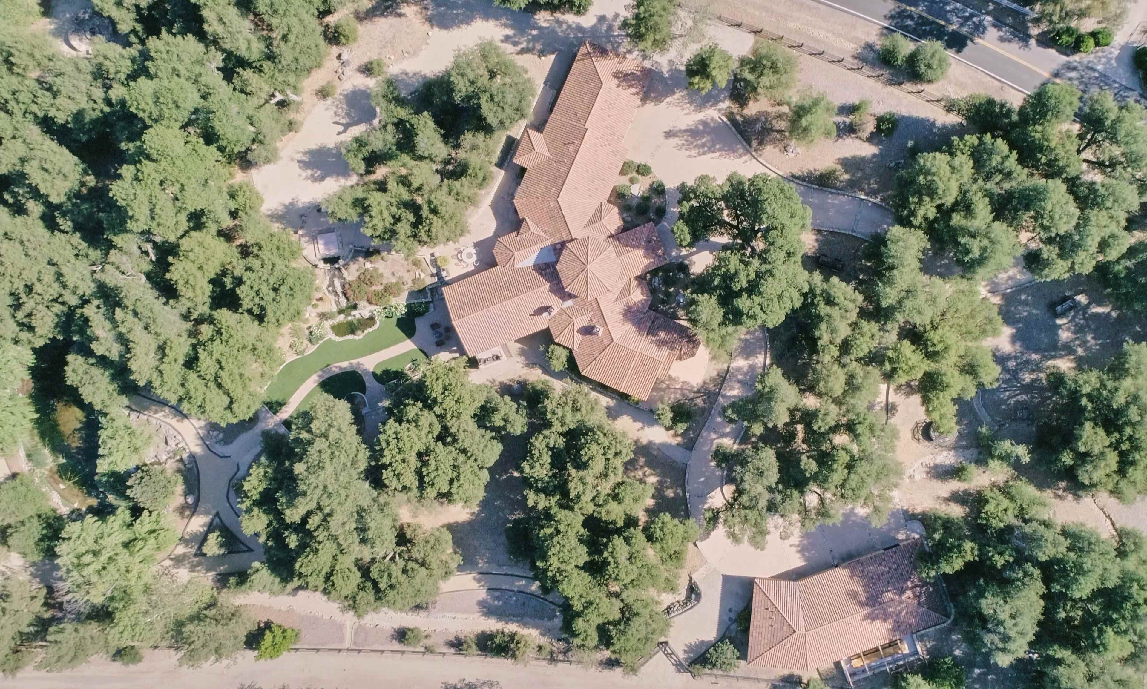 An aerial view of a large property with multiple buildings surrounded by trees and landscaped areas.