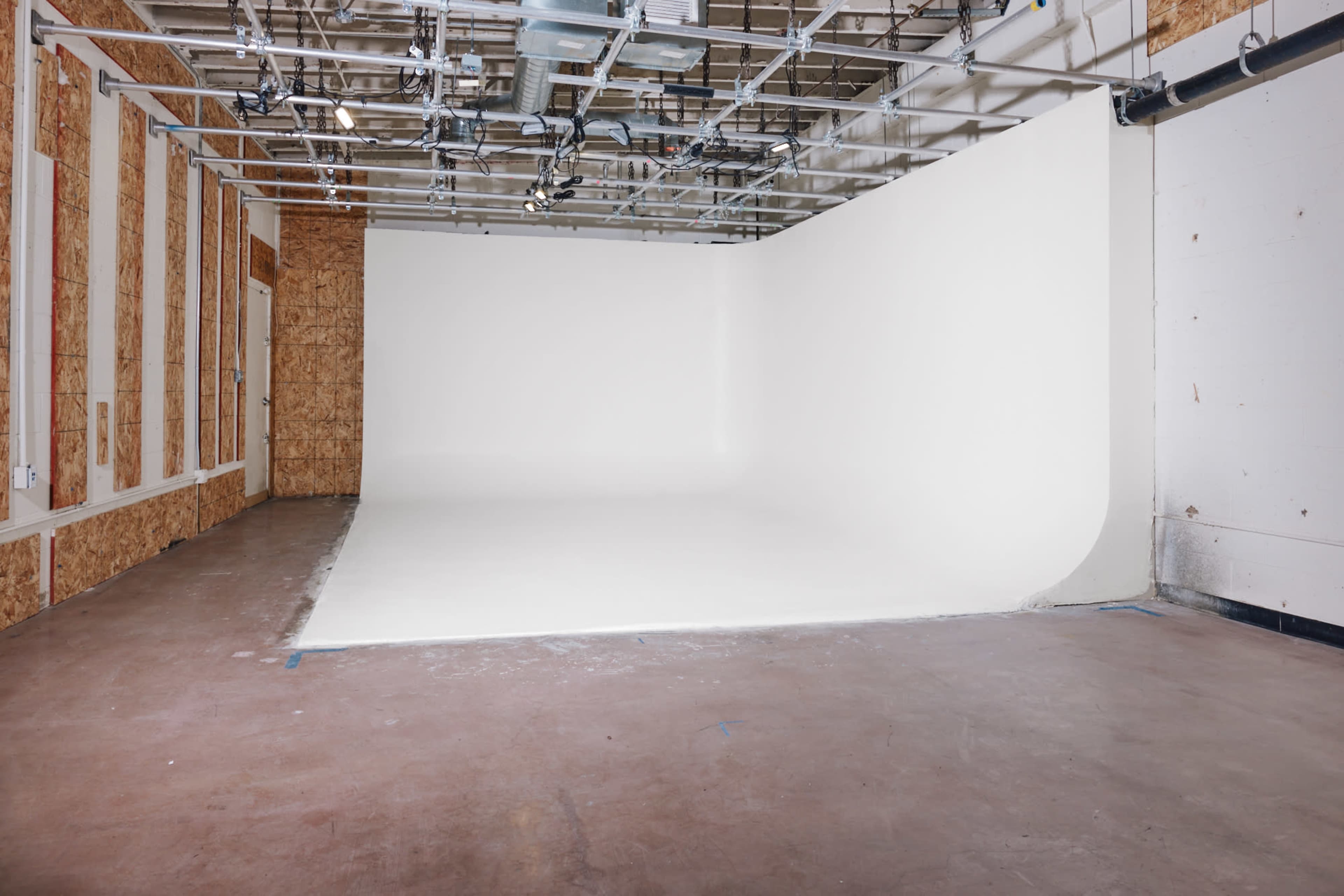 The image shows a spacious white-walled studio with a seamless backdrop and a floor that transitions smoothly into the wall.