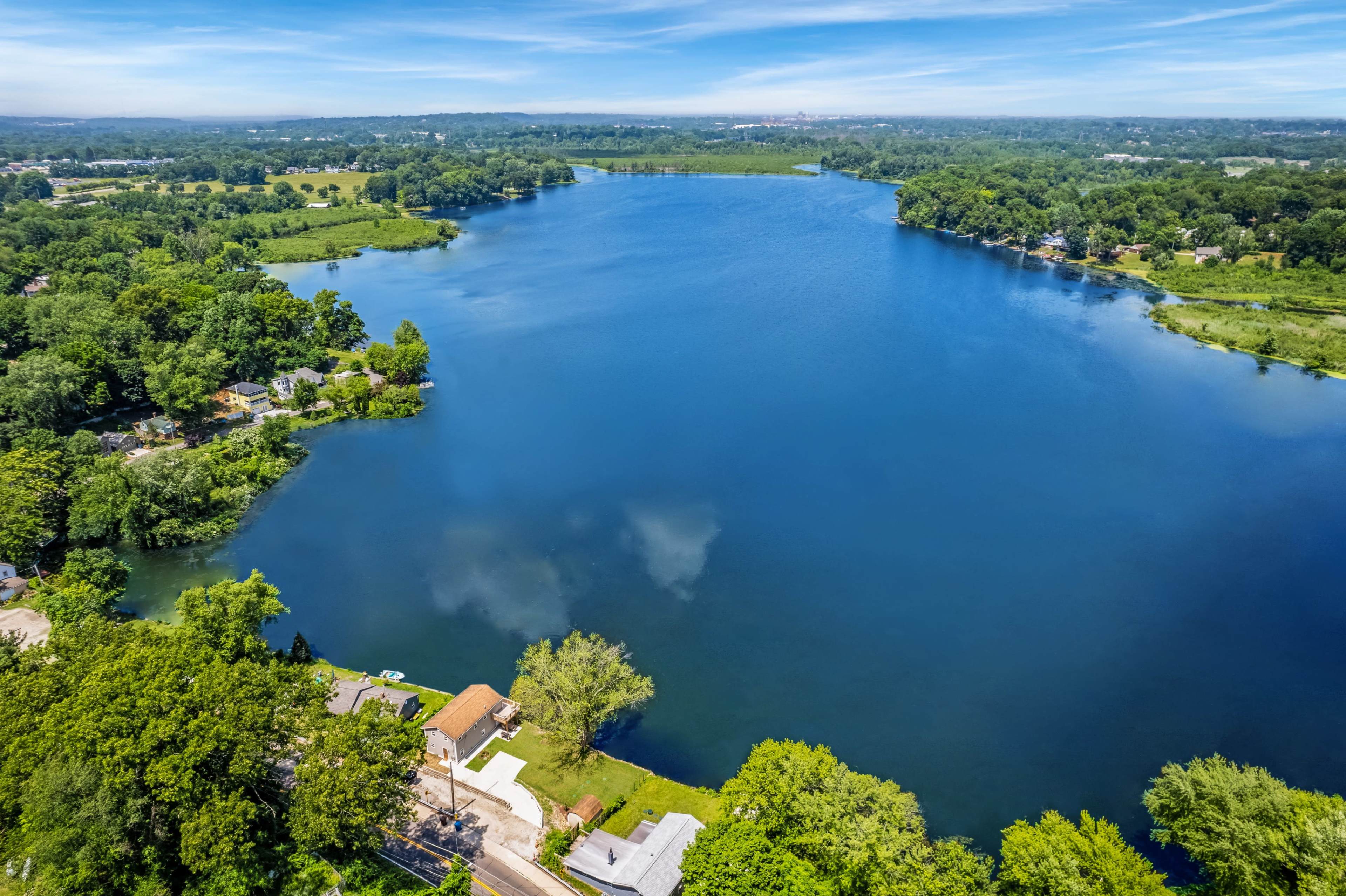 An aerial view of a large, tranquil lake surrounded by lush greenery and residential properties along its shoreline.