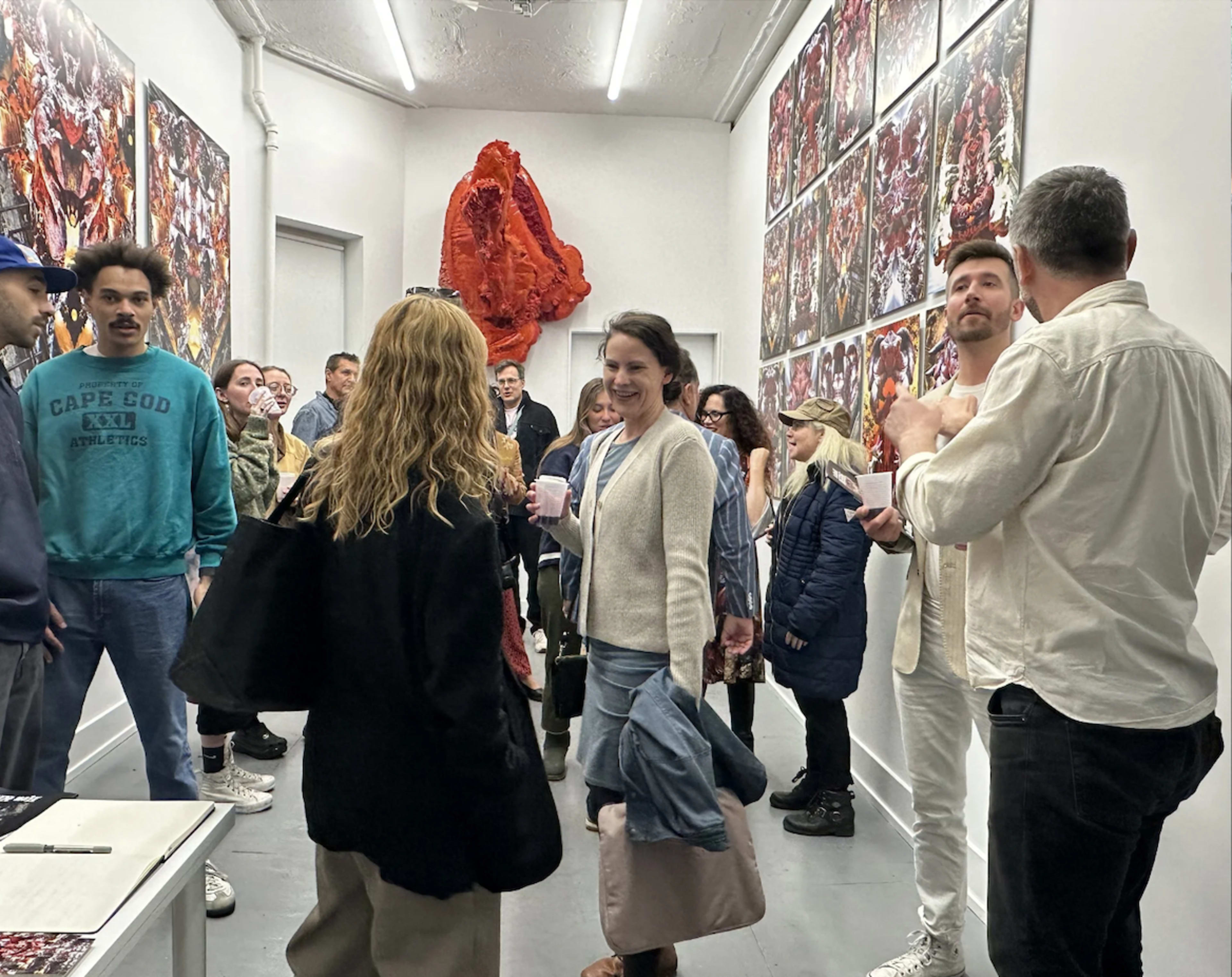 A group of people stands in an art gallery surrounded by large, vibrant artworks on the walls.