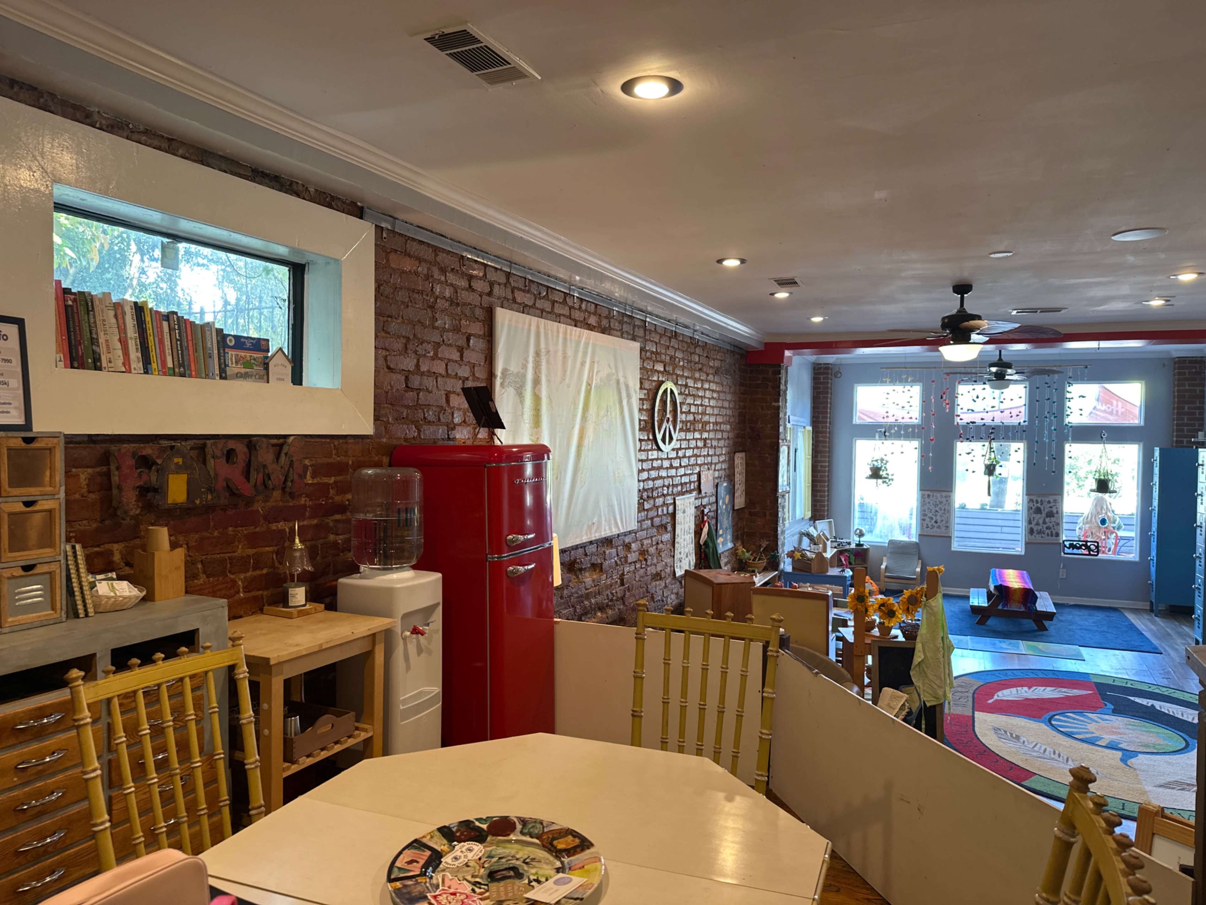 The image shows a cozy interior of a café featuring exposed brick walls, a red vintage refrigerator, and a variety of seating options including tables and chairs.