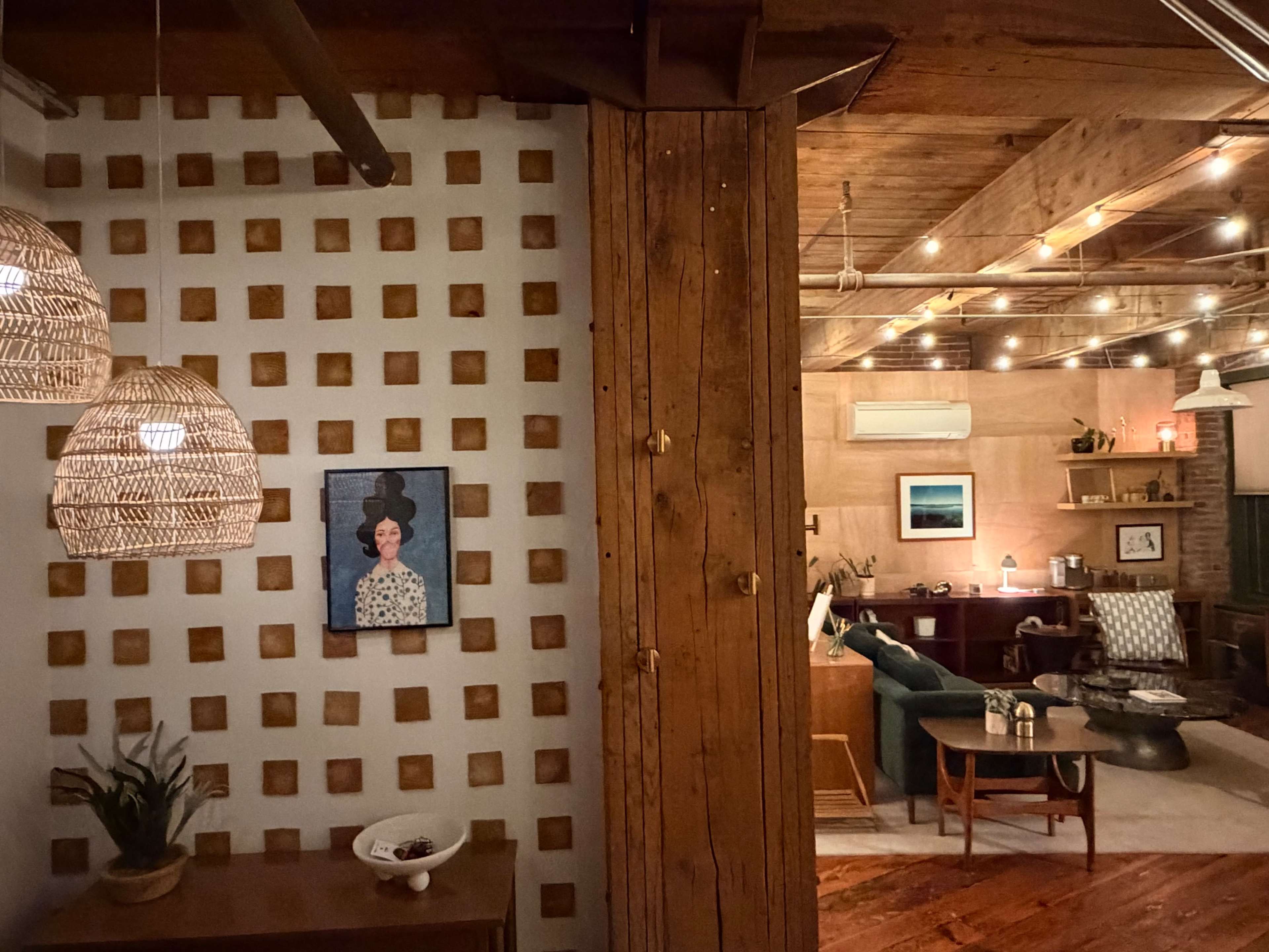 The image shows a cozy indoor space featuring a decorative wall with a portrait, wooden elements, and warm lighting.