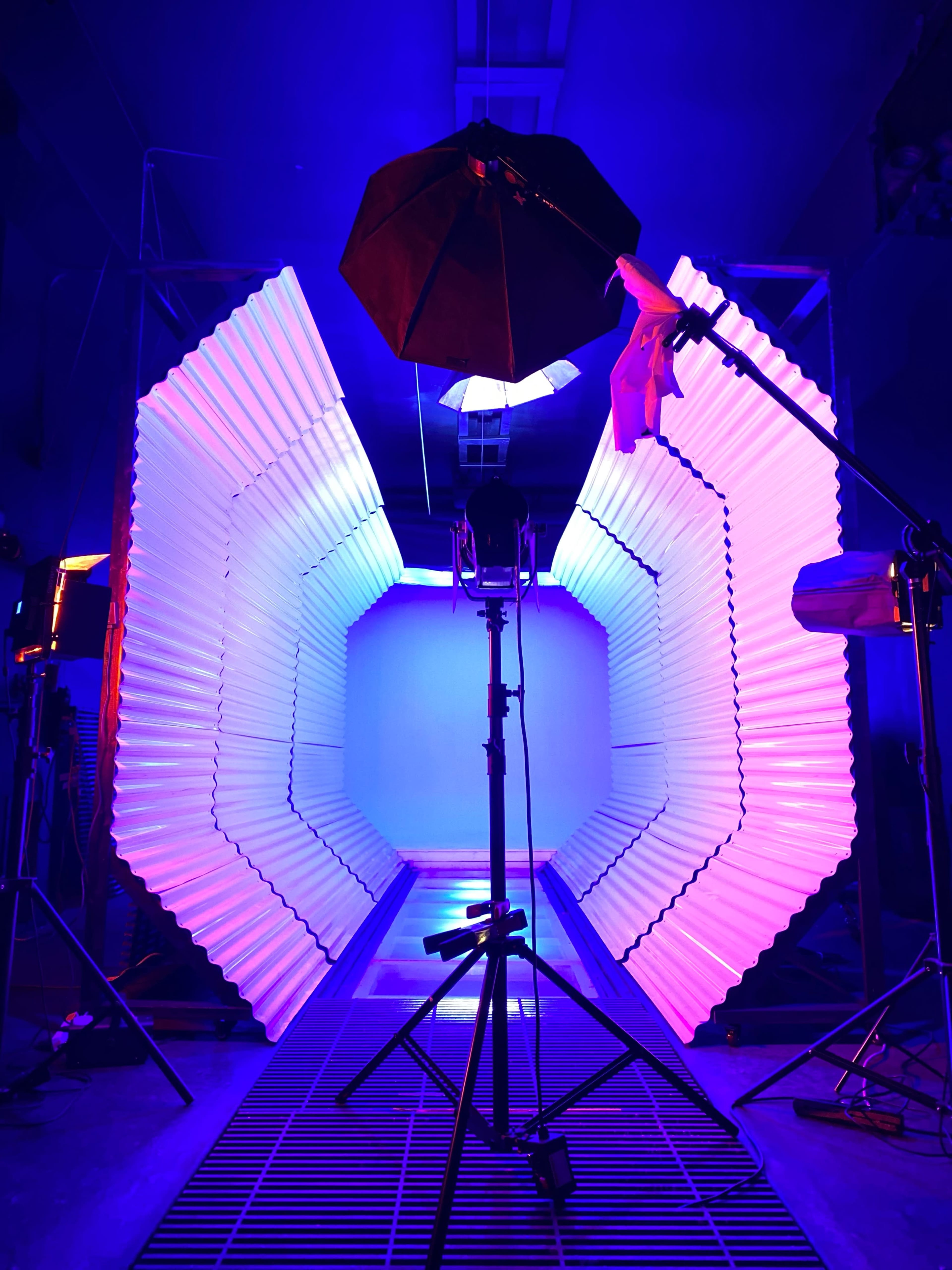 A photography studio features a backdrop with illuminated, curved panels and a professional lighting setup.