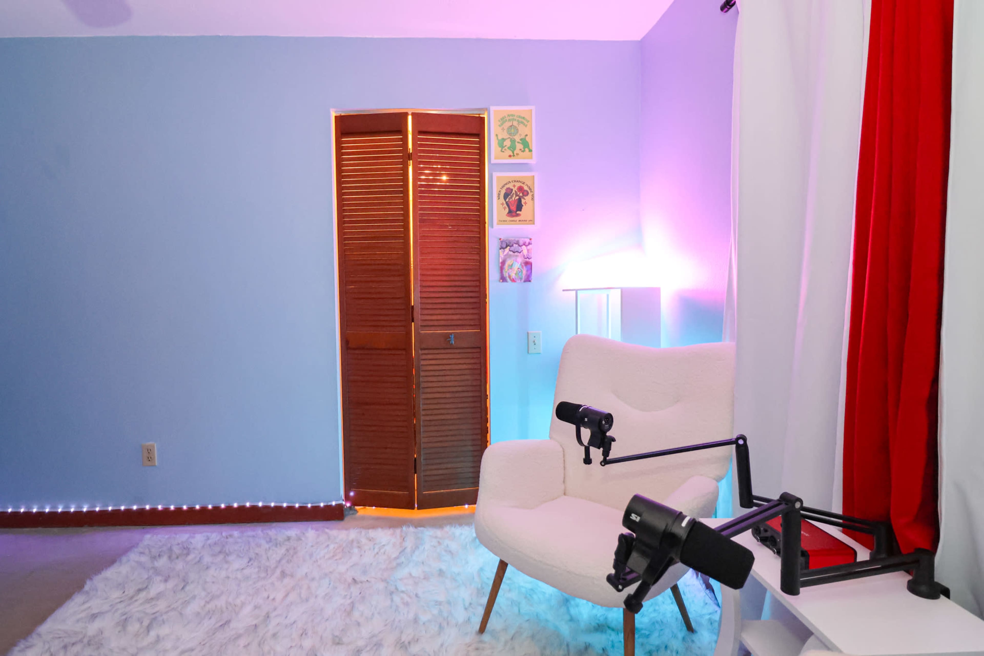 The image shows a cozy room with a light blue wall, a white chair, a microphone on an adjustable stand, and a closet with wooden doors.
