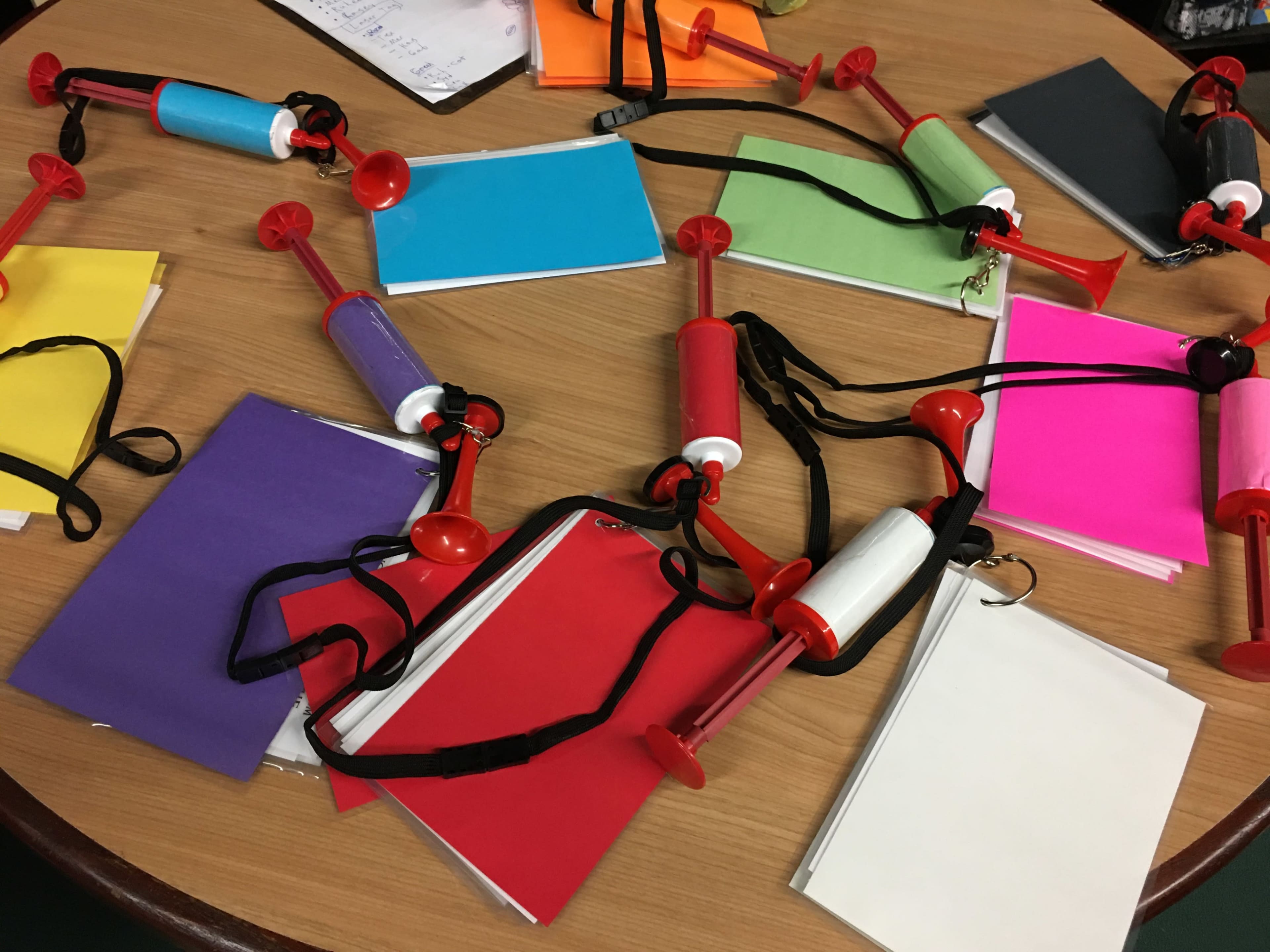 Several colorful notebooks are arranged on a table, connected by toy megaphones.
