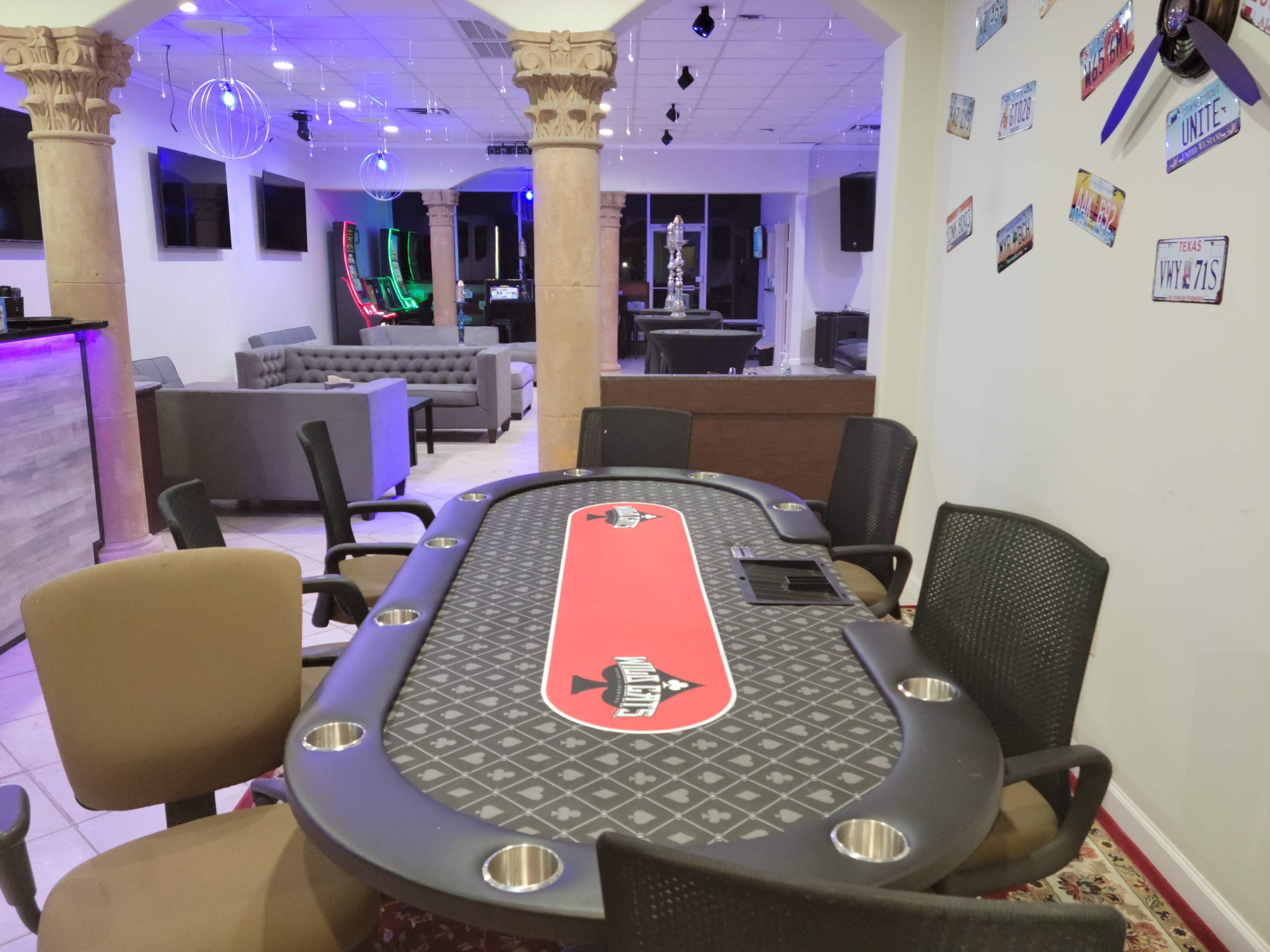 A poker table at a gaming establishment, surrounded by chairs and with a lounge area visible in the background.
