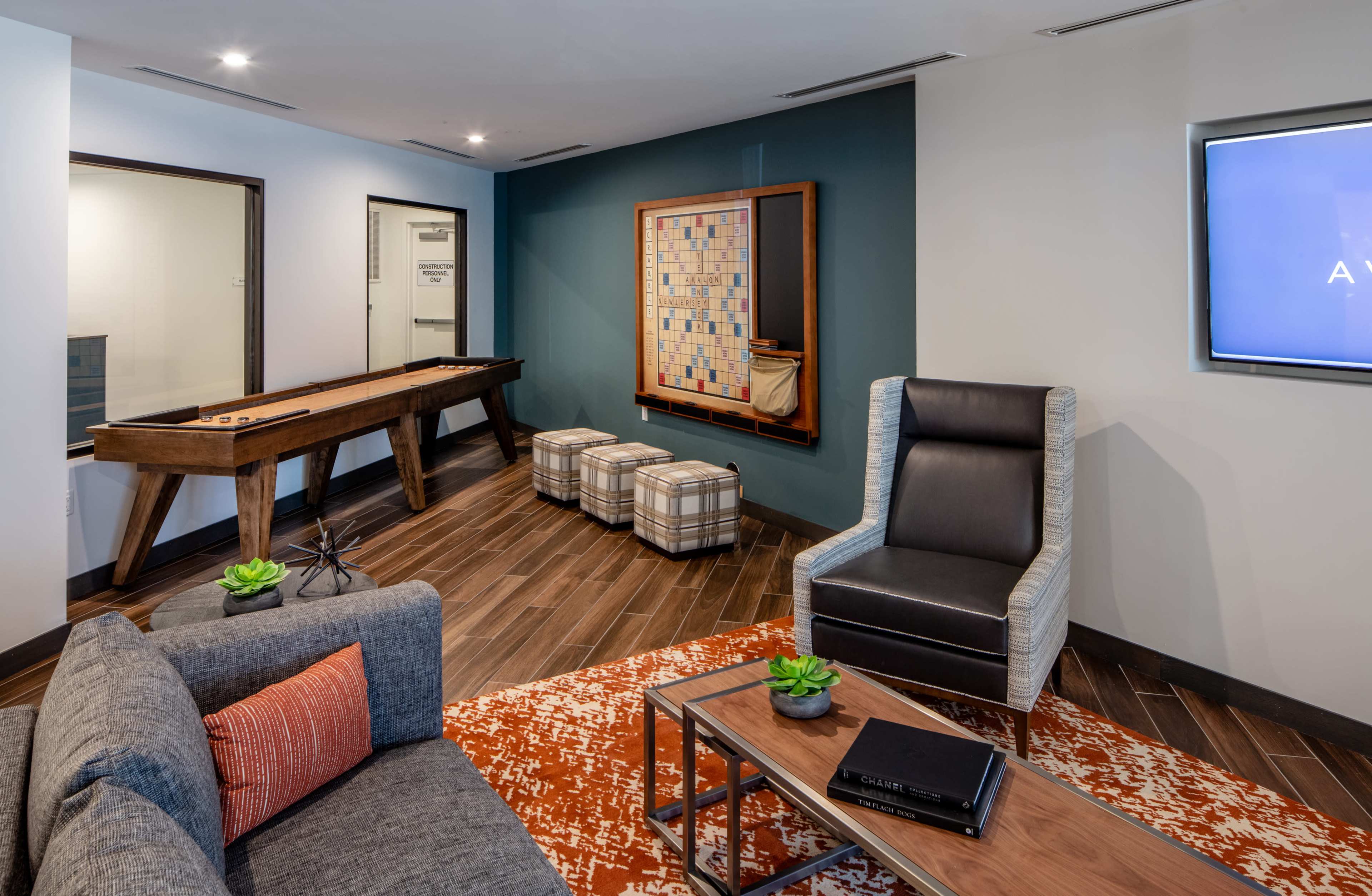 A lounge area featuring a shuffleboard table, a modern sofa, and decorative seating with plants on a coffee table.