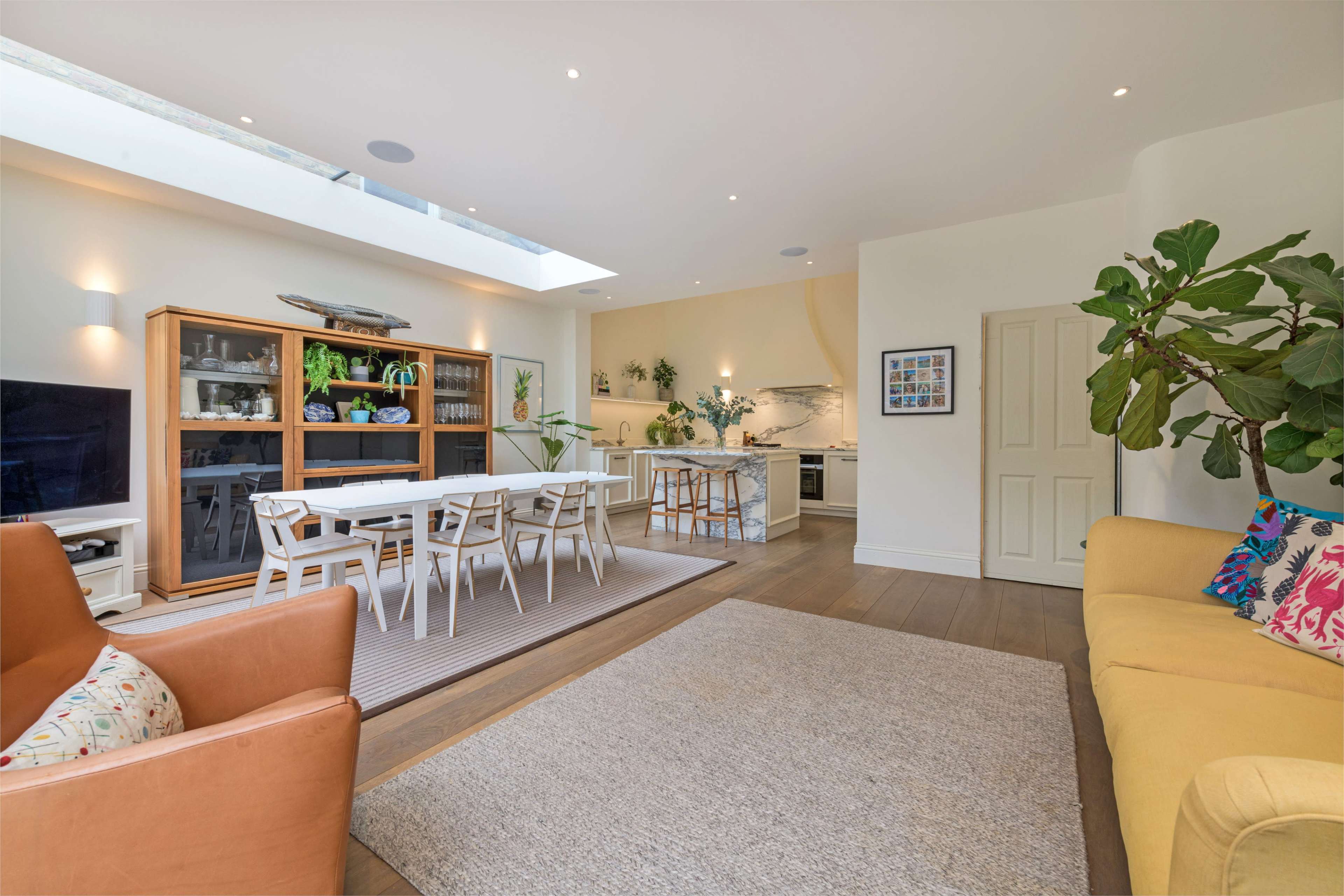 A bright and spacious open-plan living area featuring a dining table, a kitchen, and a cozy seating arrangement.