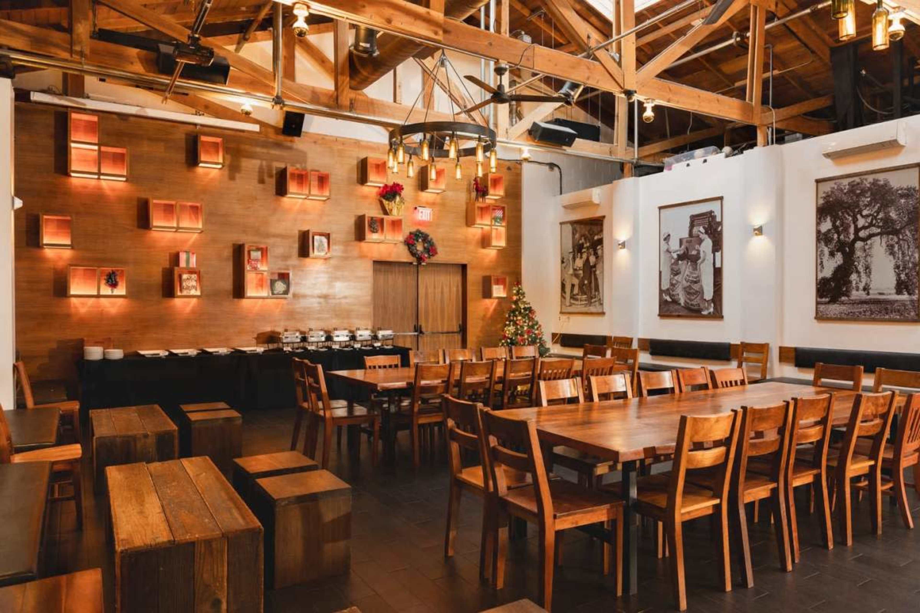 The image shows a spacious restaurant interior with wooden tables and chairs, adorned with rustic decor and wall-mounted shelves.