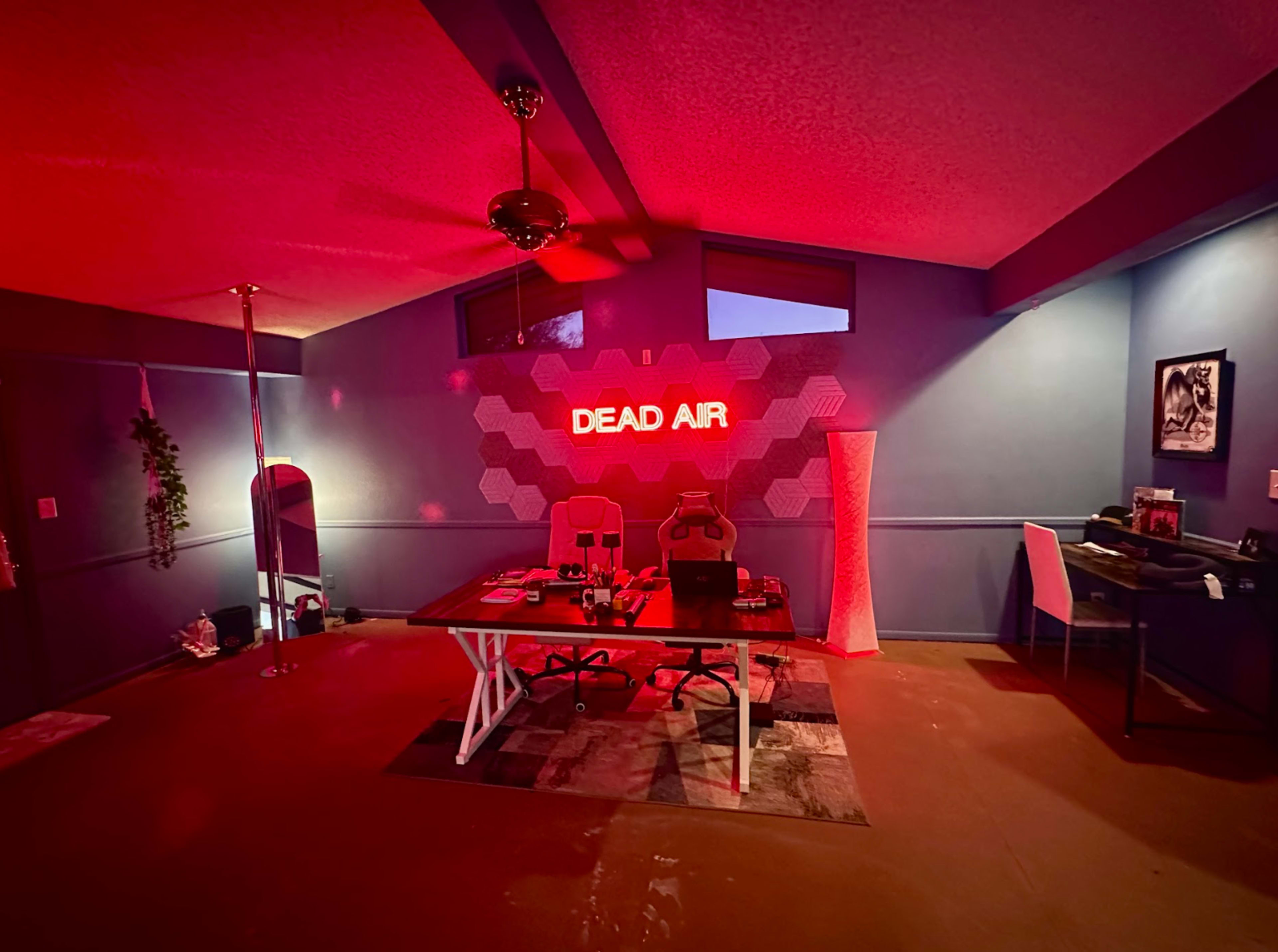 The room features a table with two chairs, a pole, and a wall displaying the words "DEAD AIR" illuminated in red light.