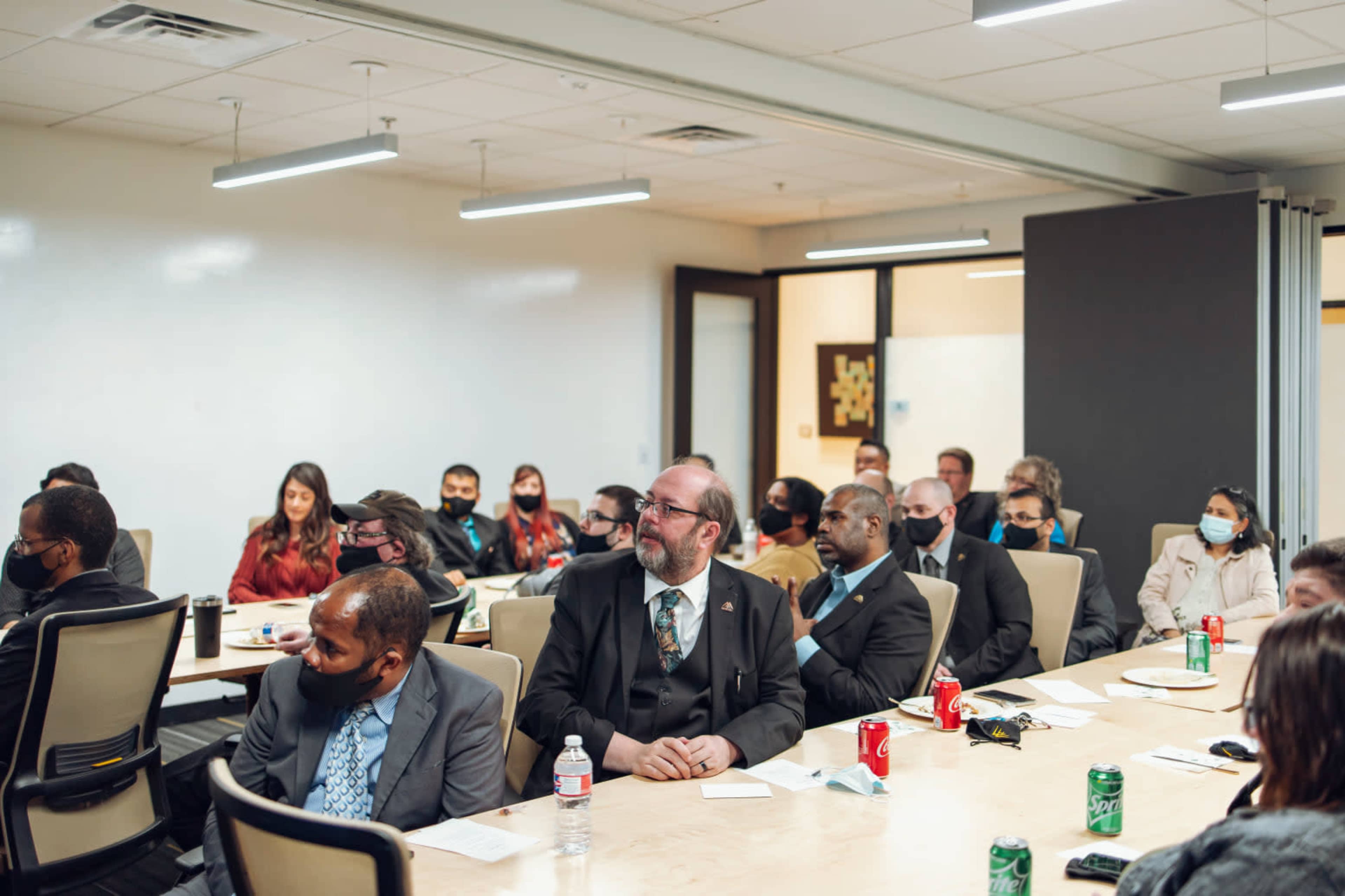 A group of people dressed in business attire listen attentively during a meeting in a conference room.
