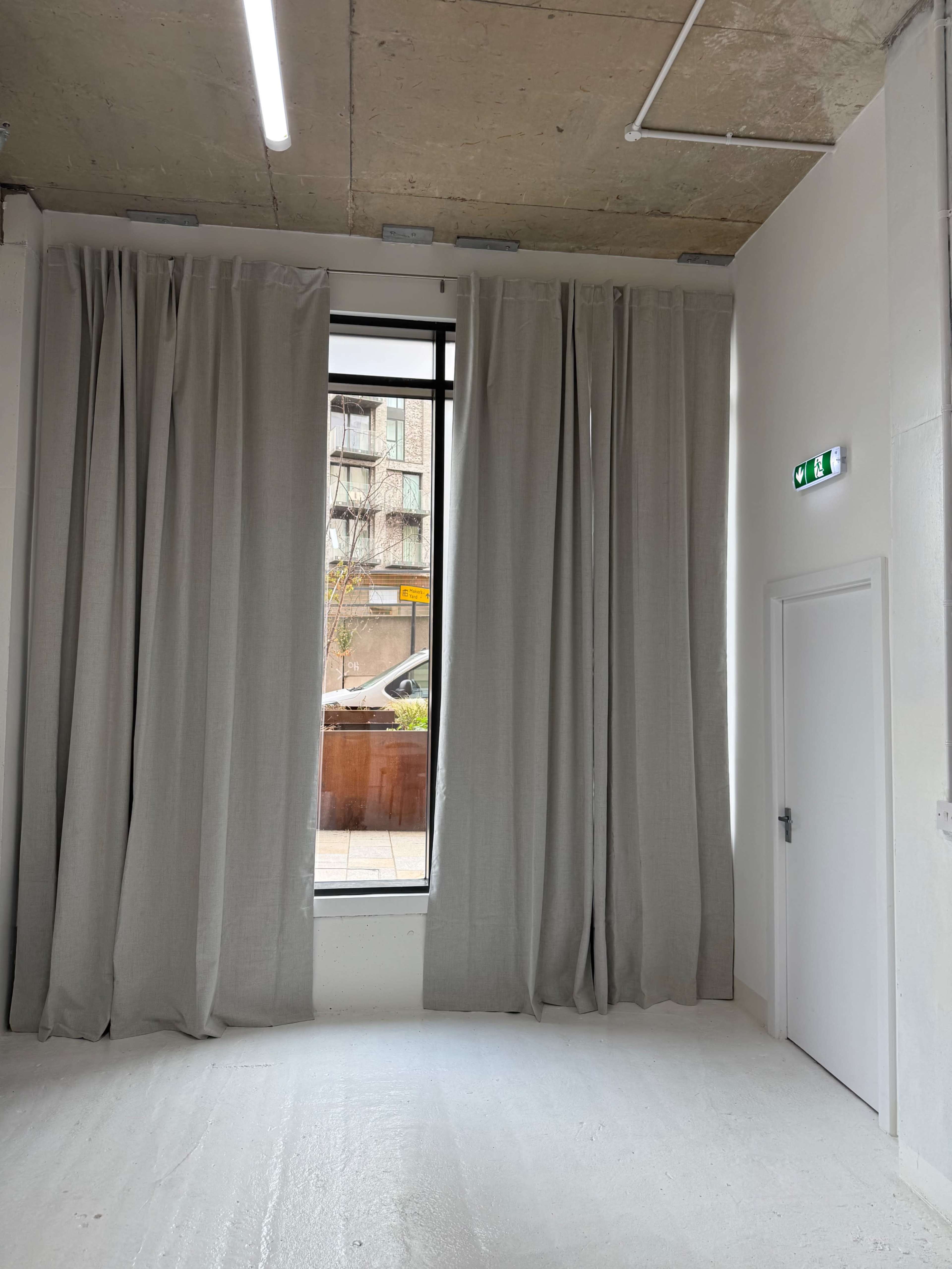 The image shows a corner of a room with large gray curtains hanging beside a window and a door on the right side.