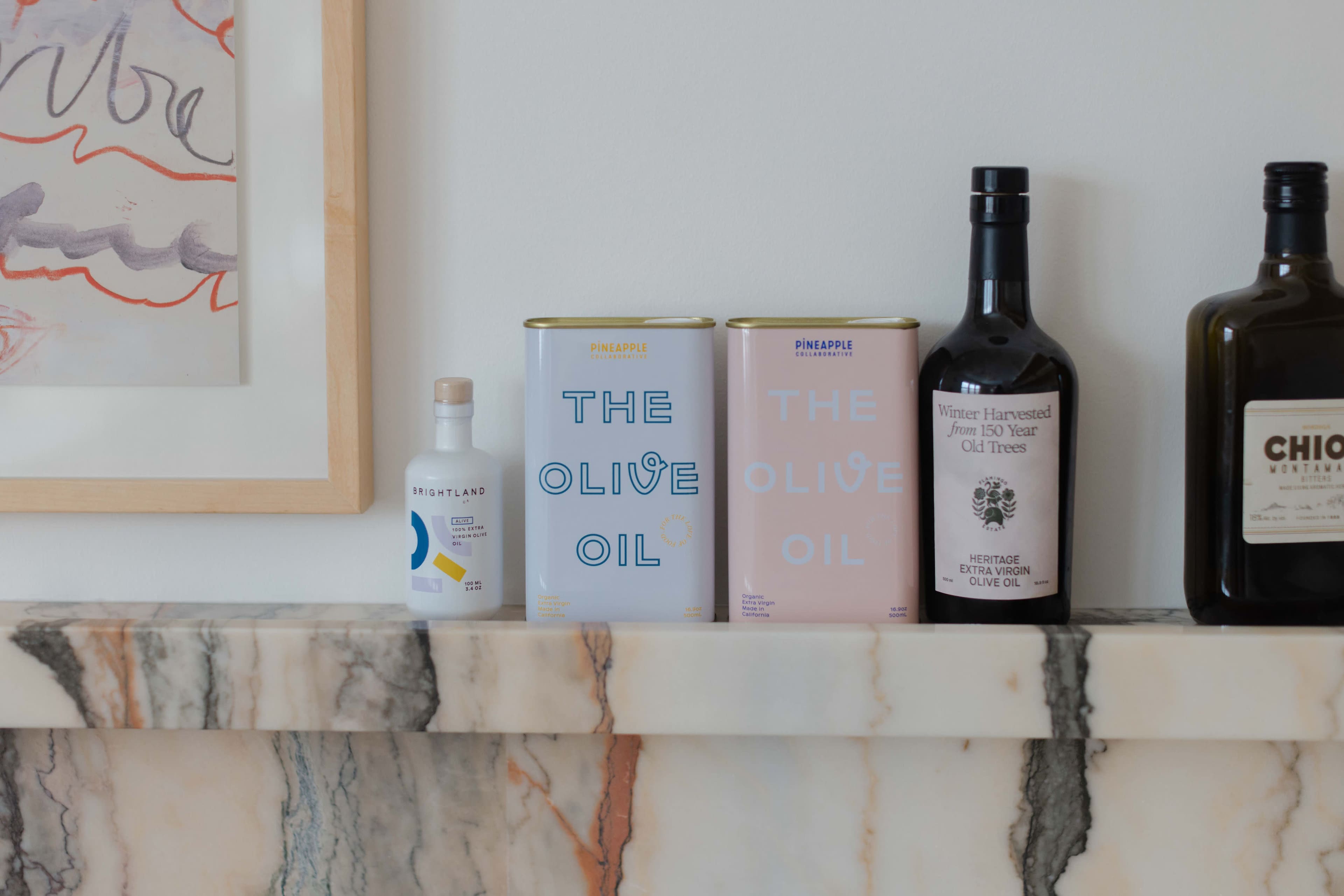 A marble mantel with three bottles of olive oil and a small bottle labeled "Brightland."