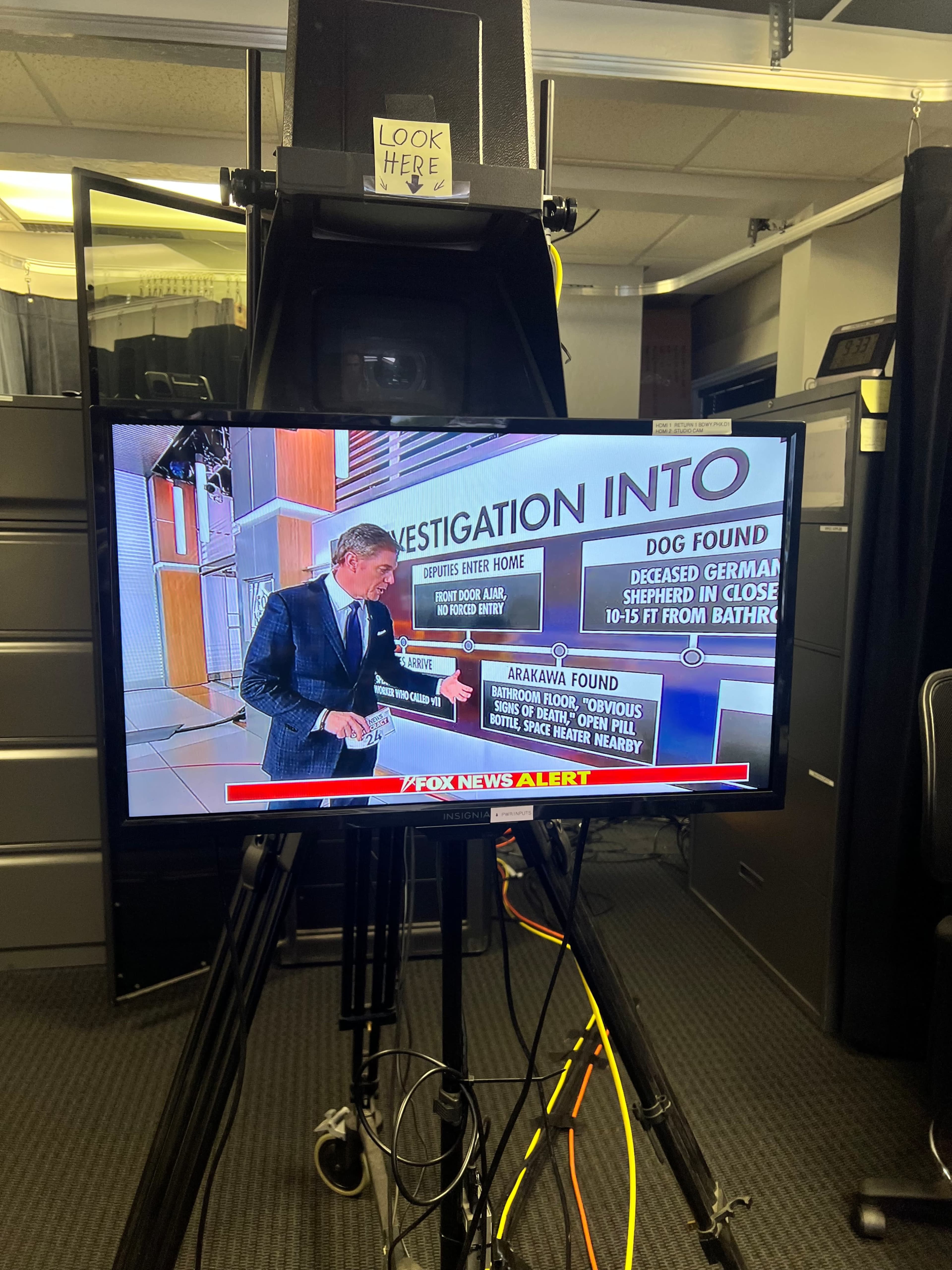 A news anchor presents a report on a television screen, highlighting an investigation involving a deceased dog found in a bathroom.