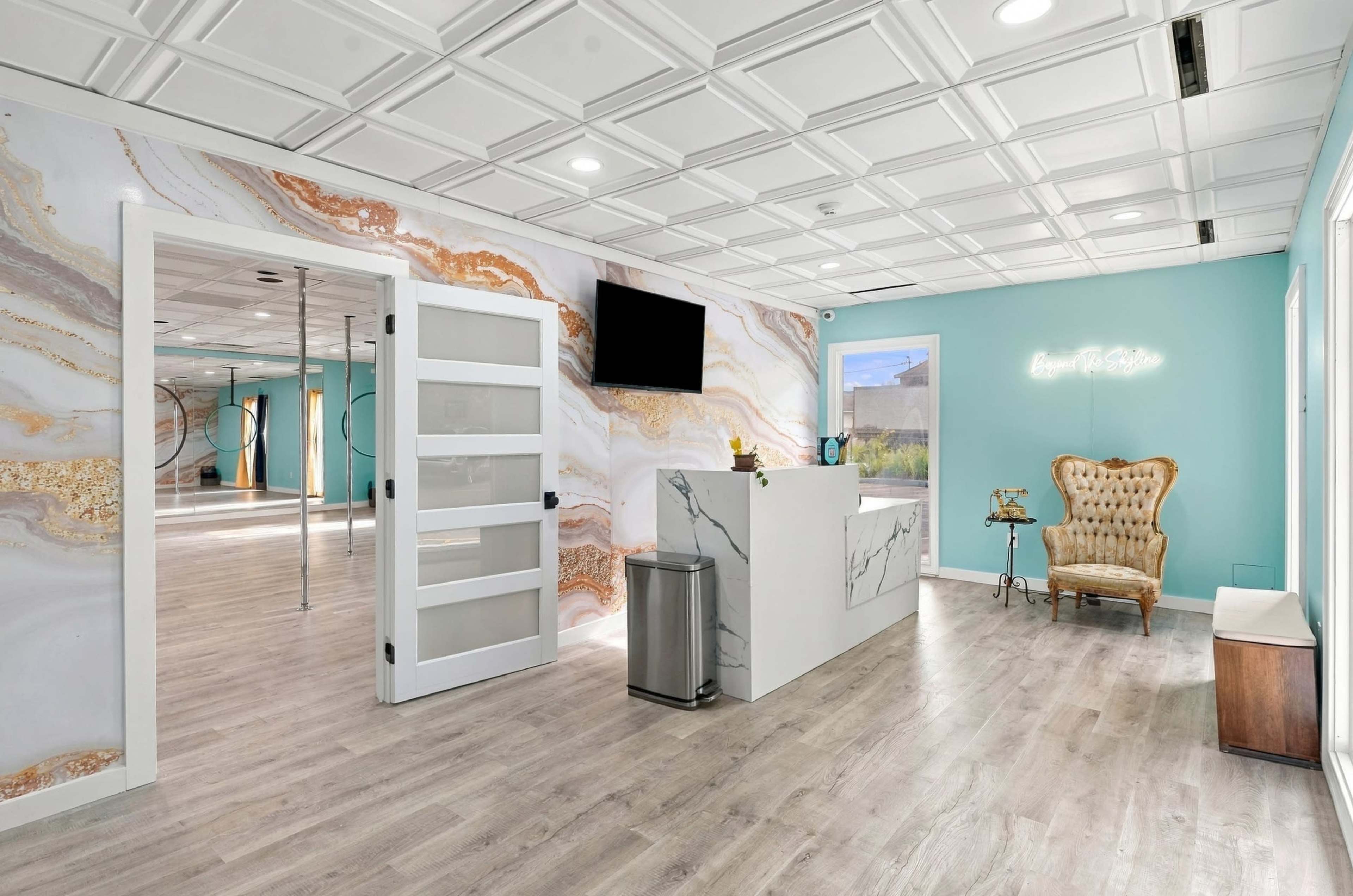 The image shows a modern reception area featuring a marble counter, a vintage-style chair, and a decorative wall with a marble pattern.