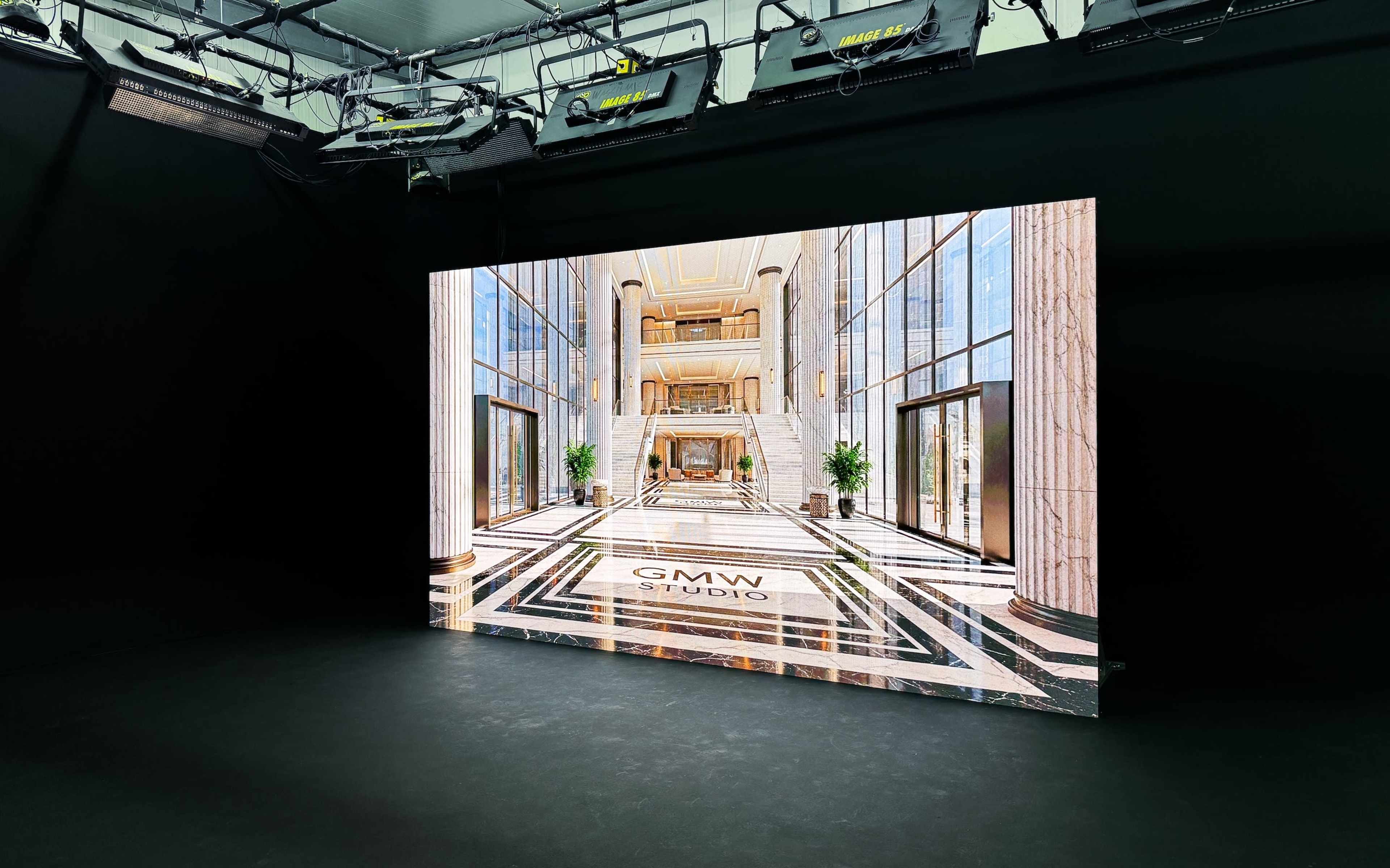 The image shows a large display screen showcasing a modern, upscale interior of a studio with marble floors and tall windows.