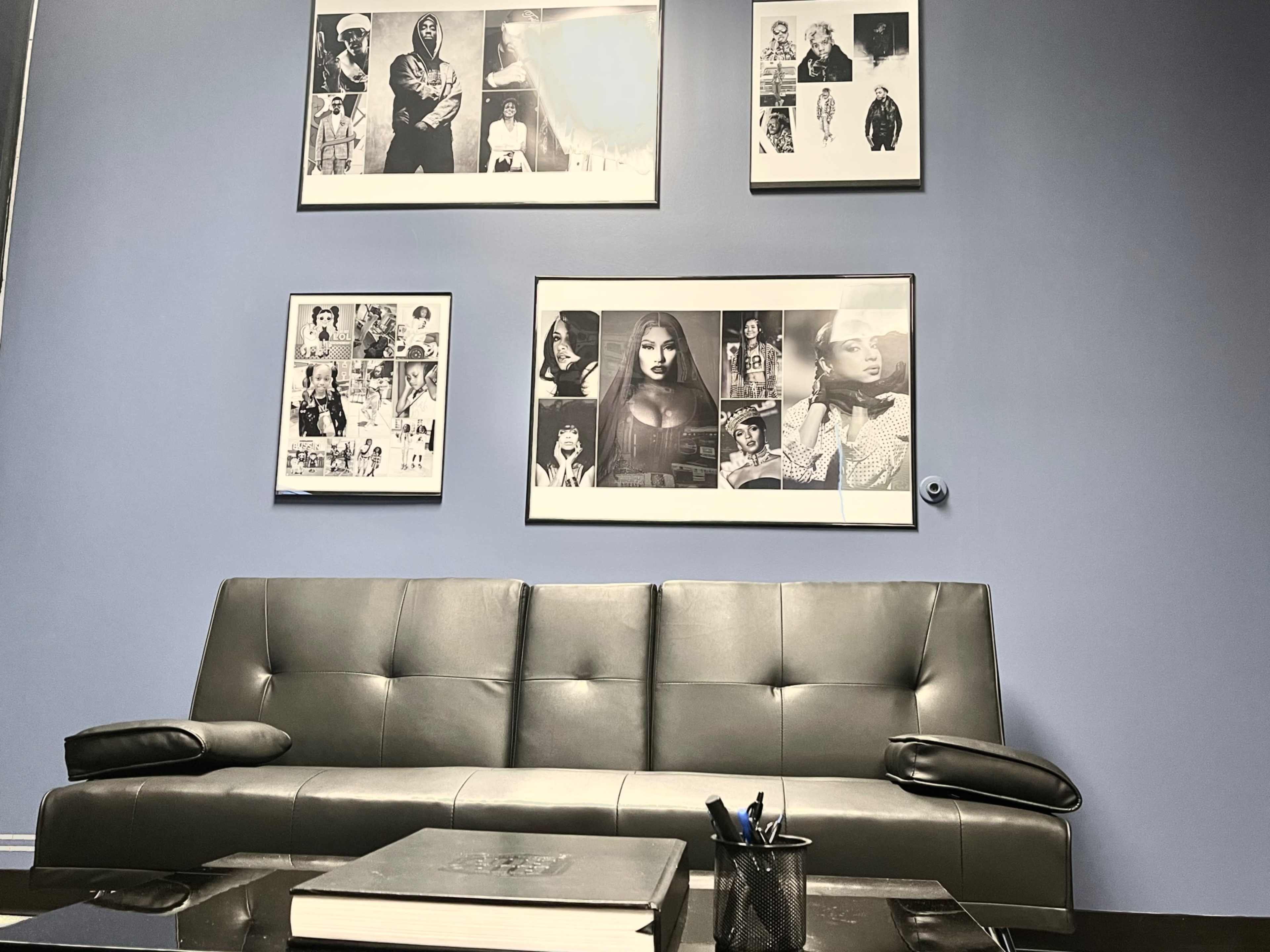 A modern gray sofa in a room with blue walls, decorated with framed black and white photographs arranged above.