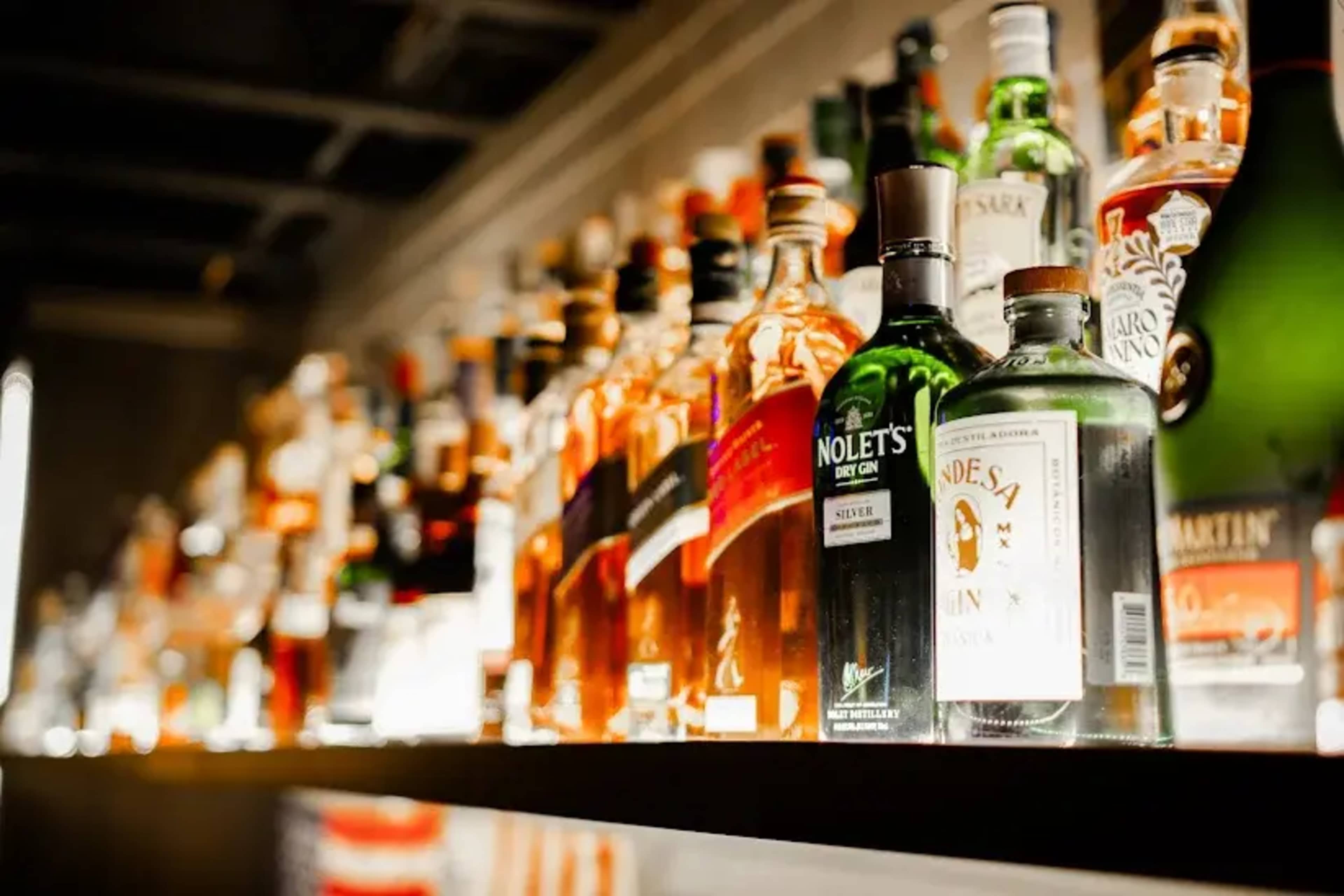 A well-stocked bar shelf displays various bottles of spirits and liqueurs arranged in a row.