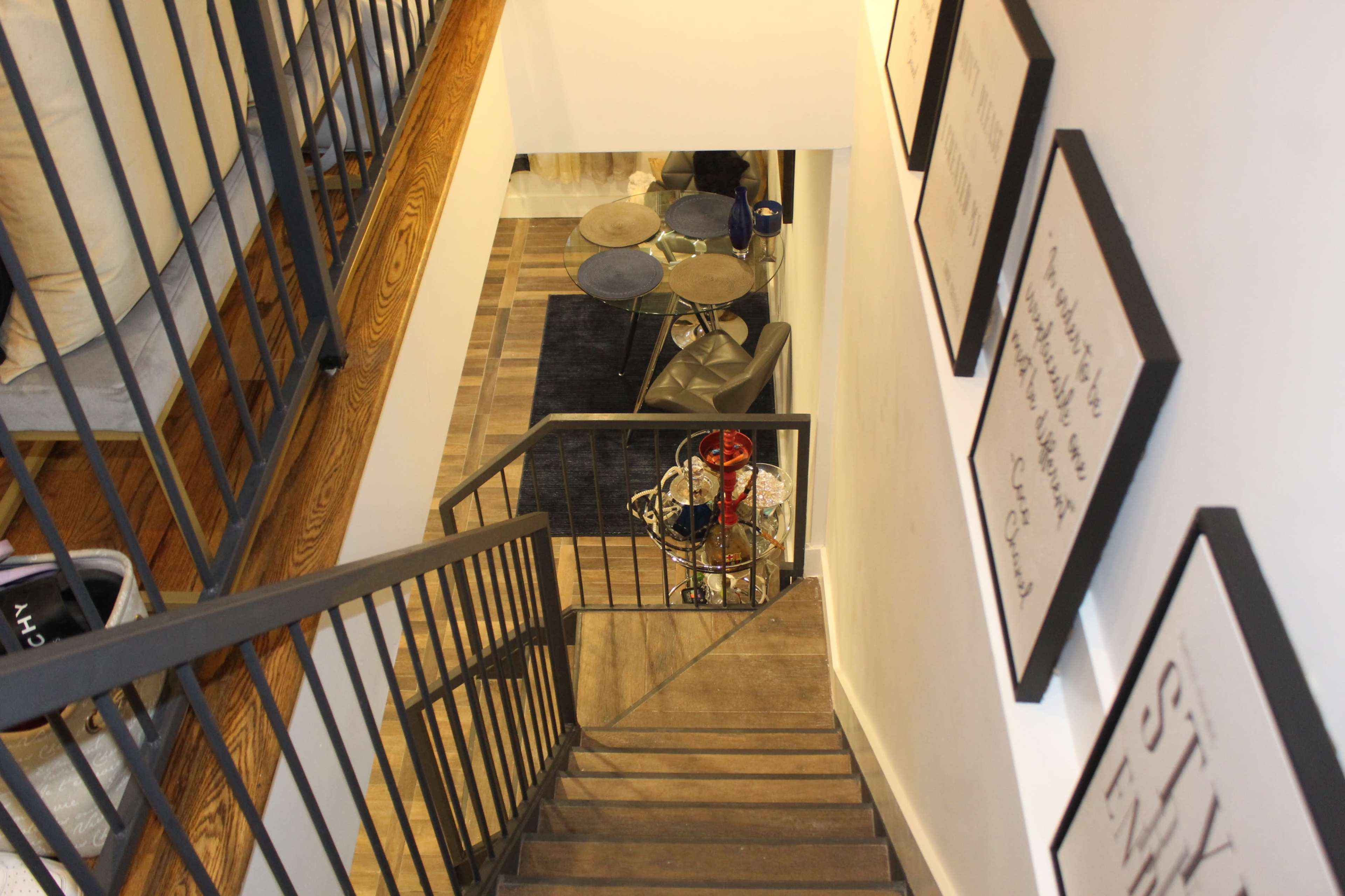A staircase leads down to a room with a set of drums and framed artwork on the walls.