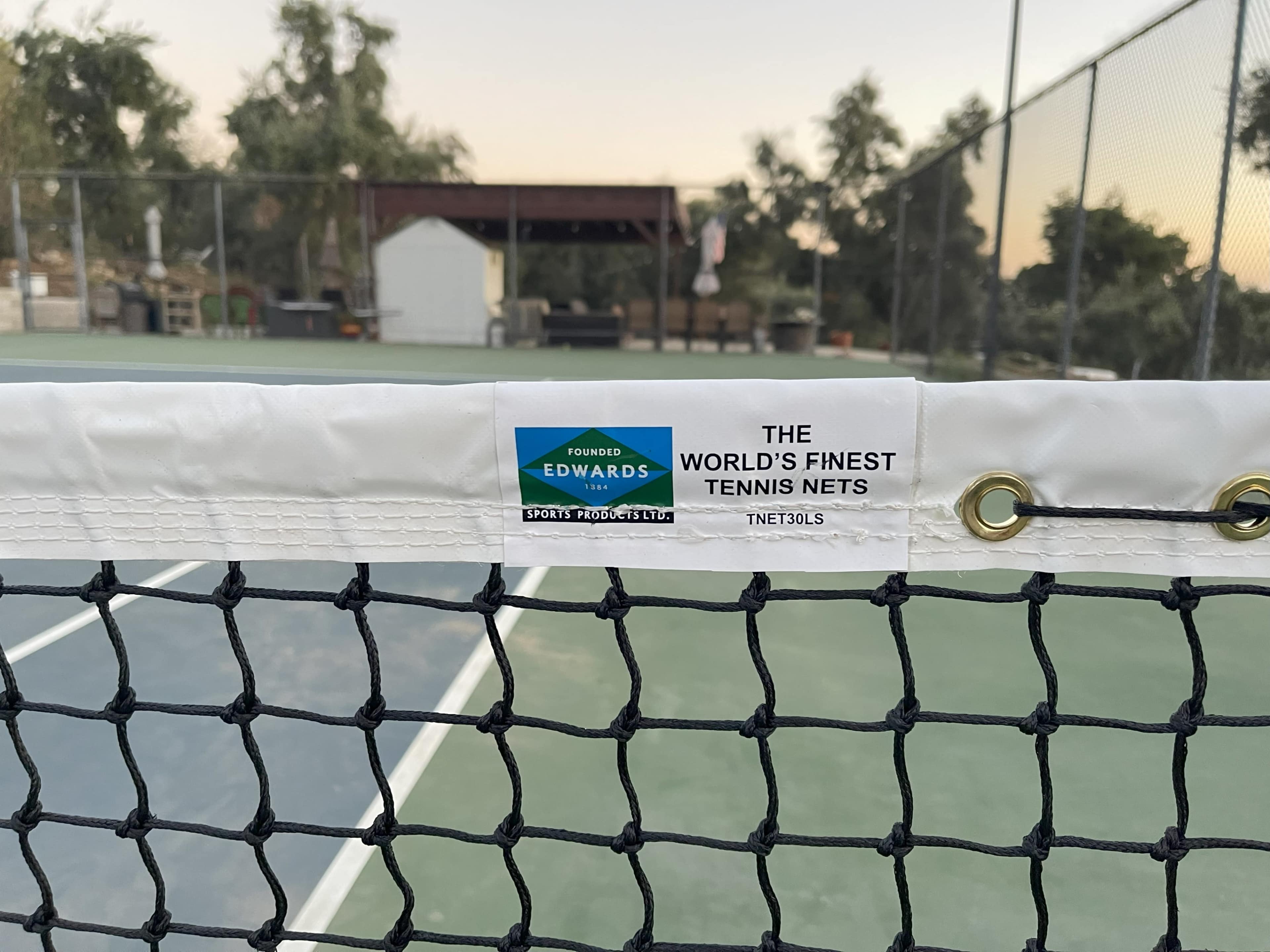 A close-up of a tennis net with a label that reads "EDWARDS THE WORLD'S FINEST TENNIS NETS" attached to it.