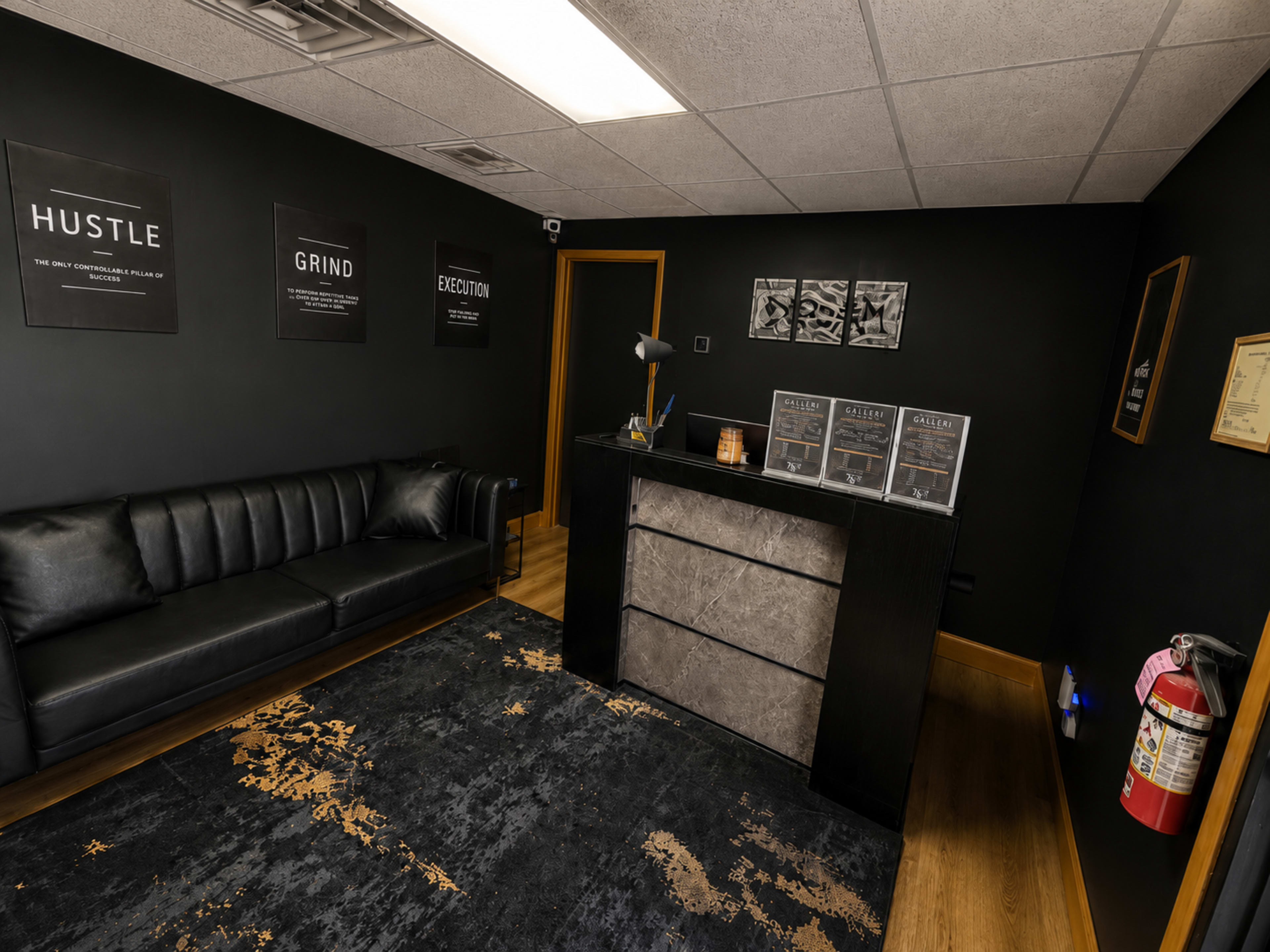 The image shows a modern office reception area with black walls, a couch, a reception desk, and motivational posters.