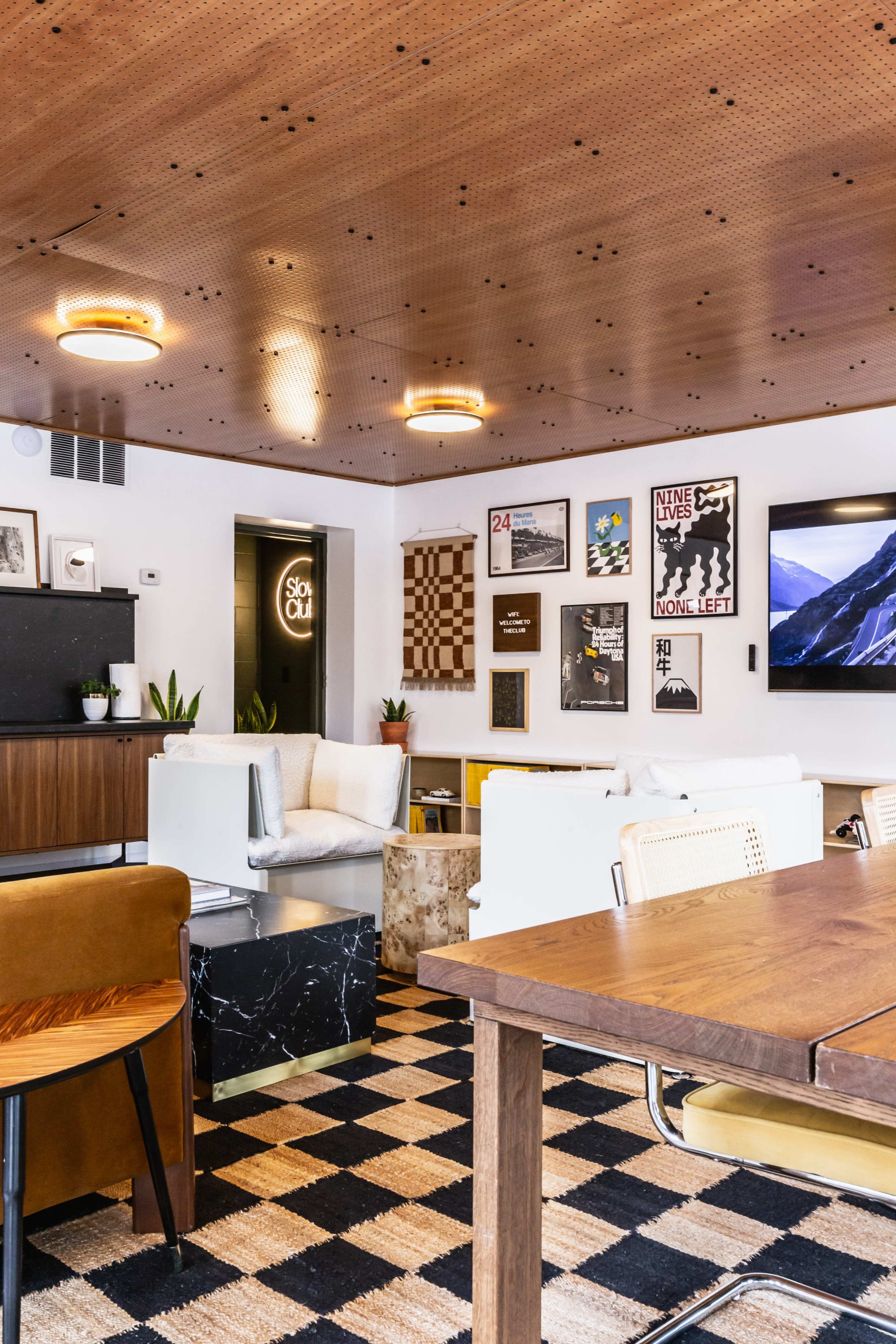 A modern, cozy lounge area with a checkerboard-patterned rug, stylish furniture, and decorative wall art.
