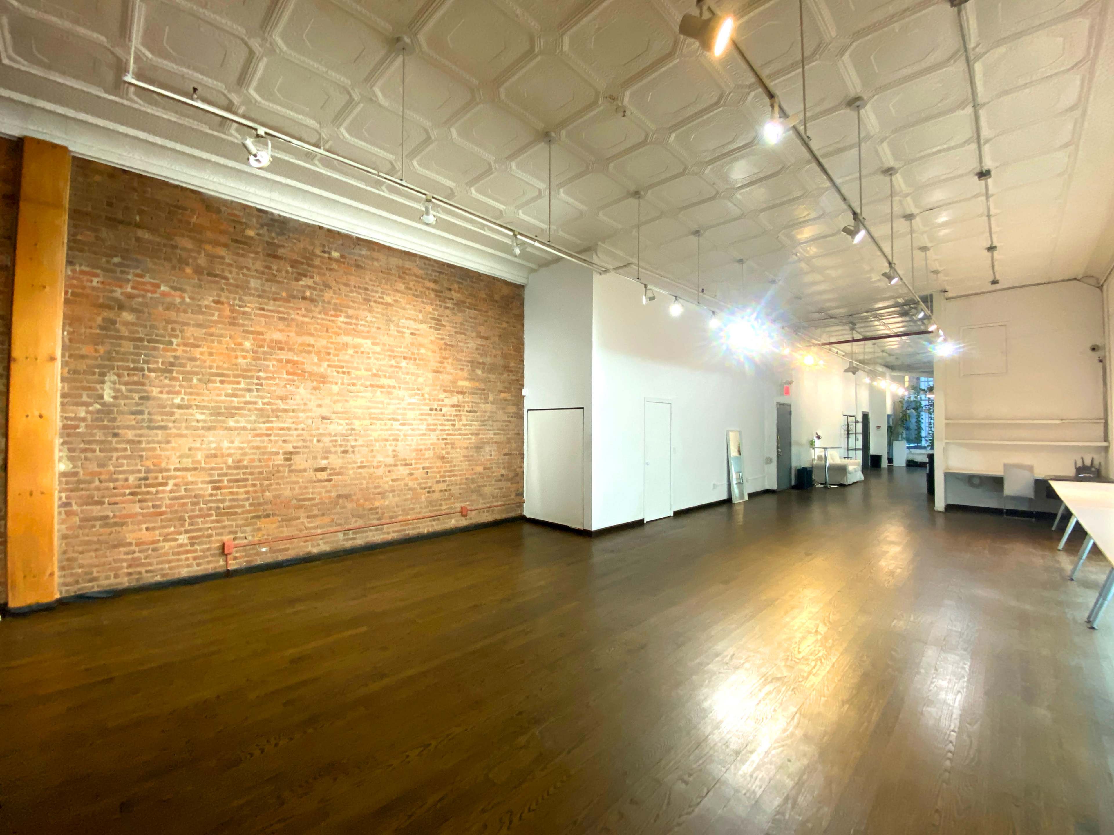 A spacious interior with exposed brick walls, polished wooden floors, and bright overhead lighting.