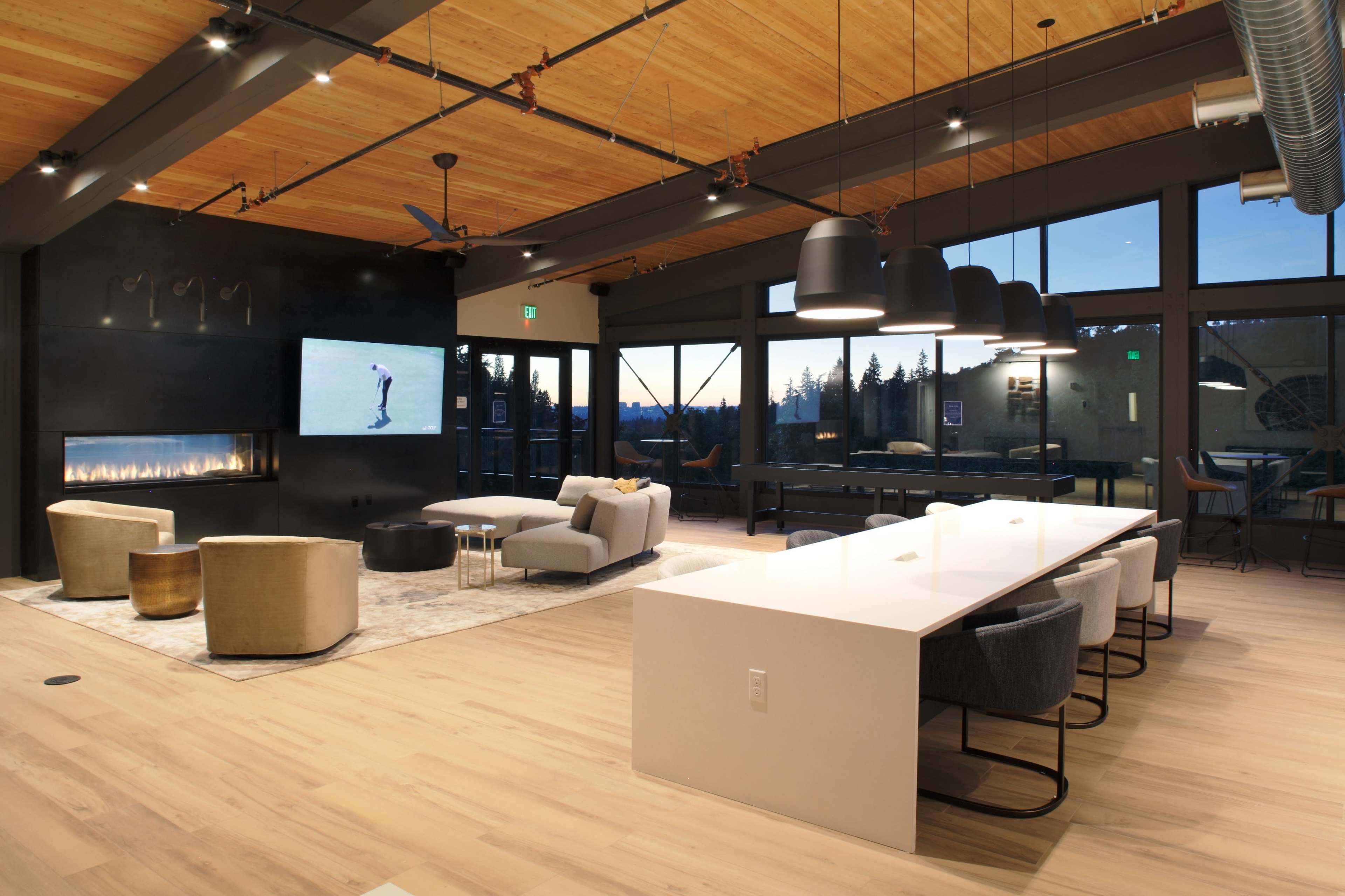 A modern, open-concept interior featuring a living area with seating, a dining table, and a large window with a view of the outdoors.