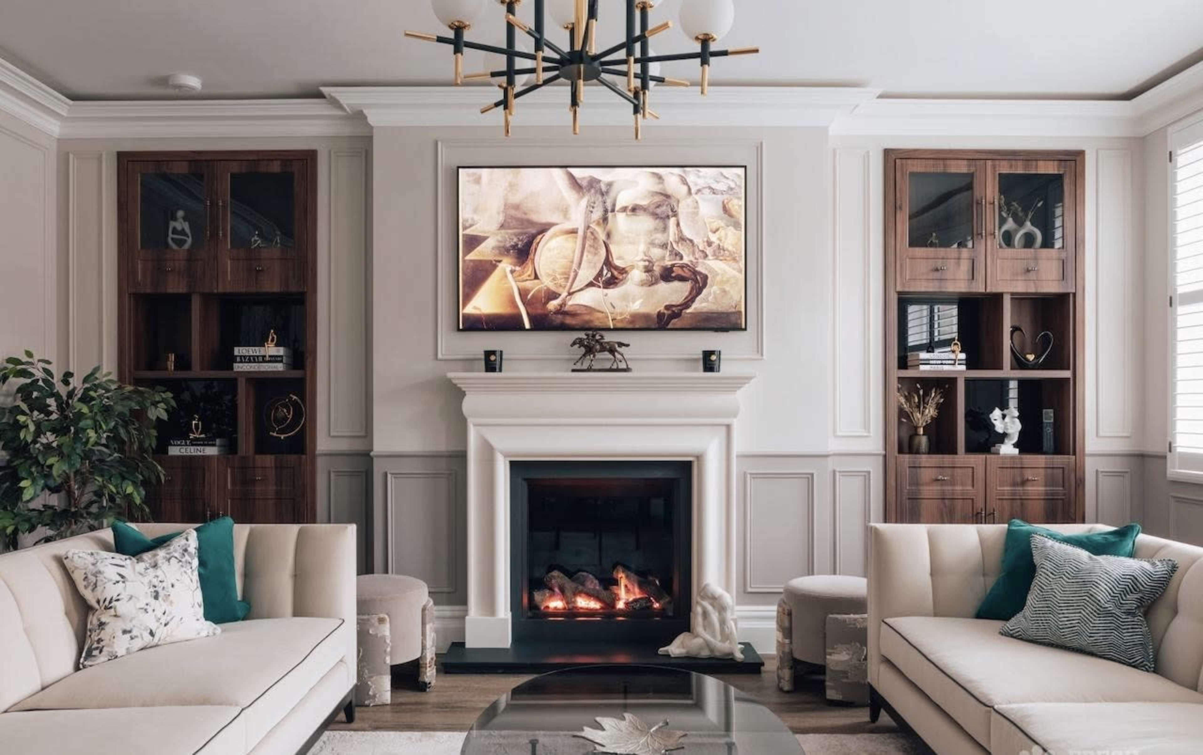The living room features two cream-colored sofas facing a fireplace beneath a television, with built-in cabinetry and decorative elements on display.