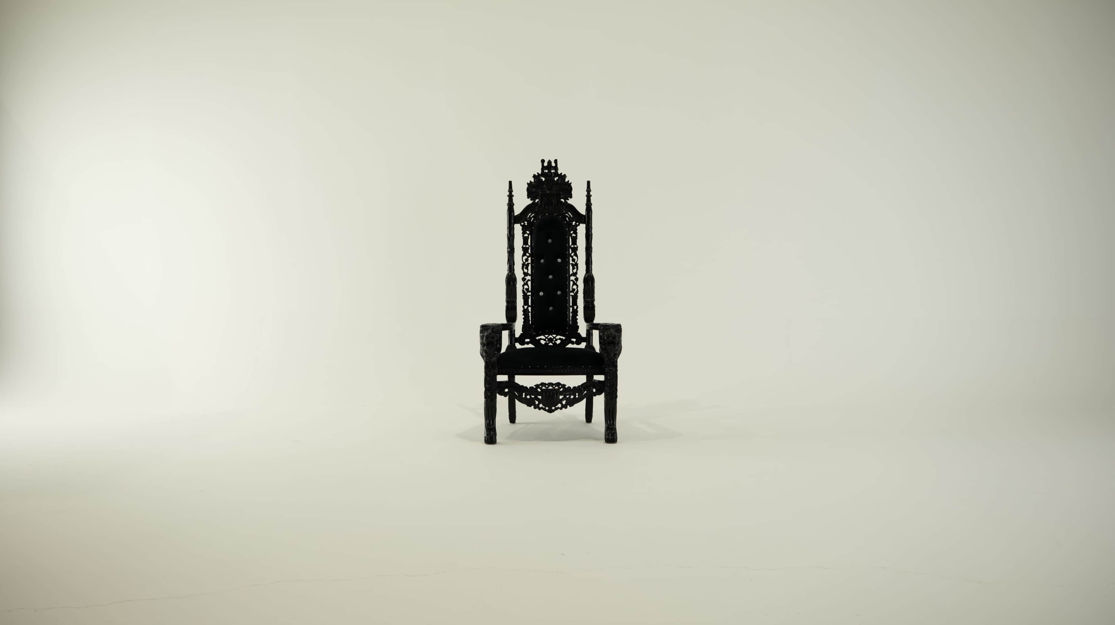 A large, intricately designed black throne is positioned in the center of a minimalist white space.