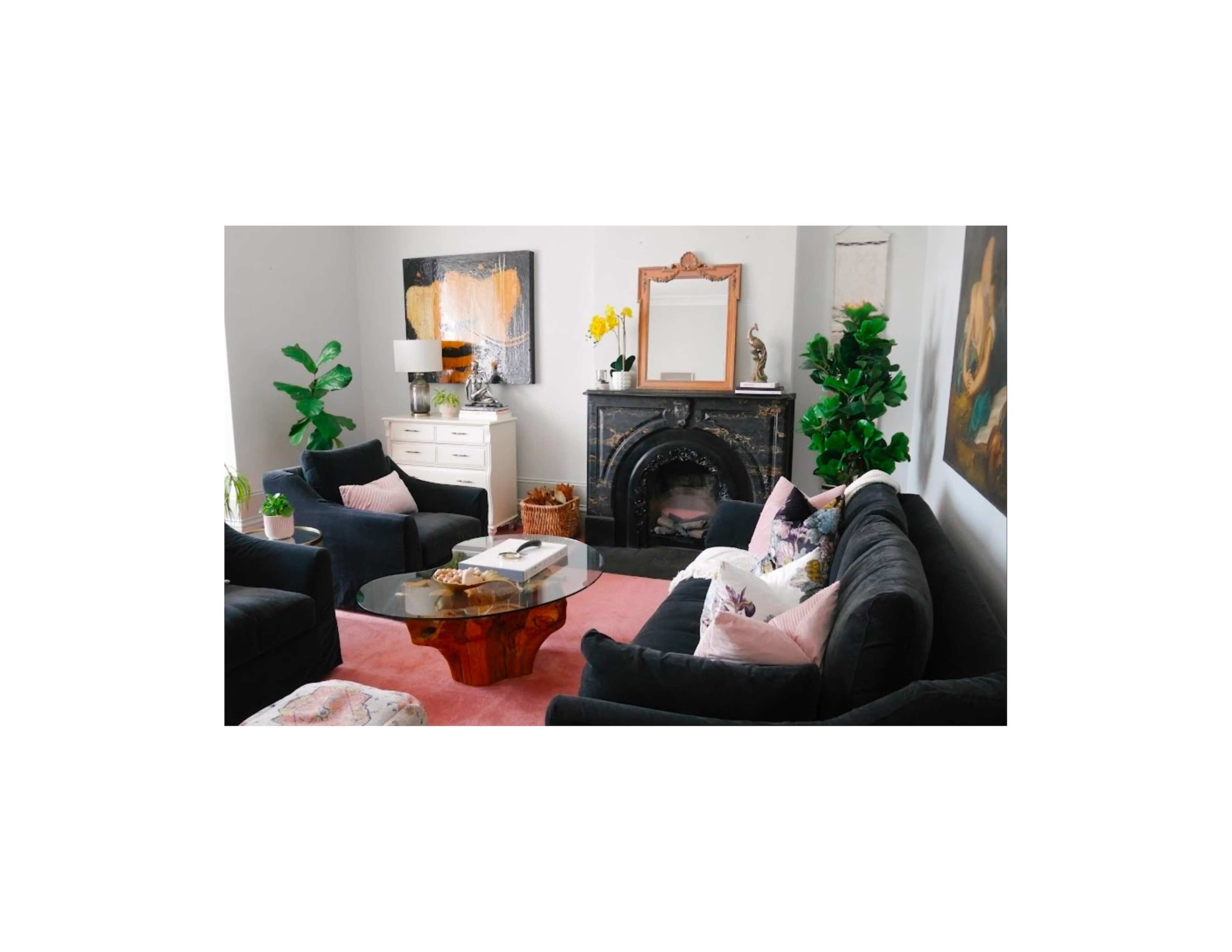 The living room features black sofas, a glass coffee table, and a fireplace, along with plants and decorative artwork on the walls.