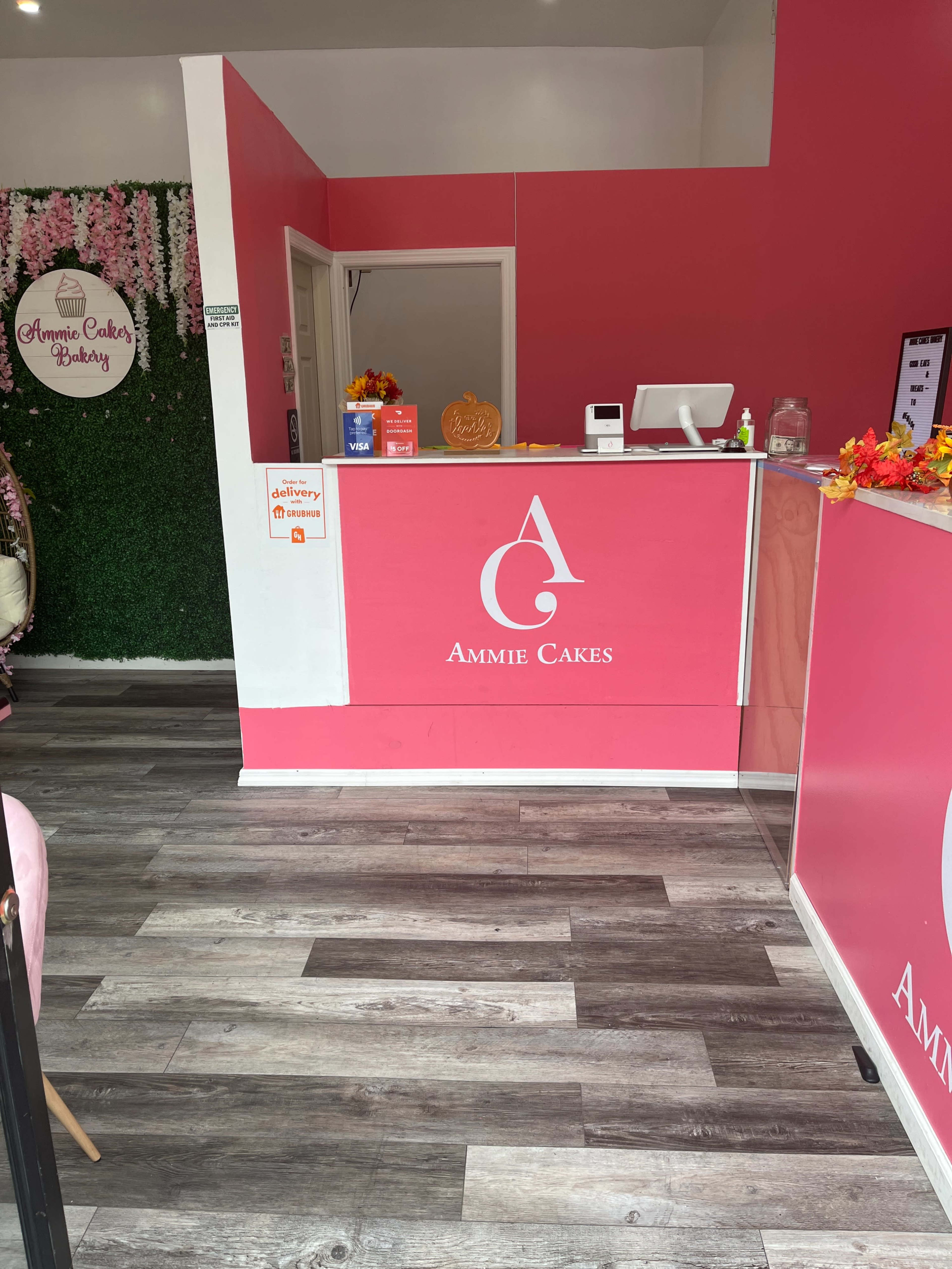 A colorful bakery interior with a pink reception counter, logo, and decorative elements.