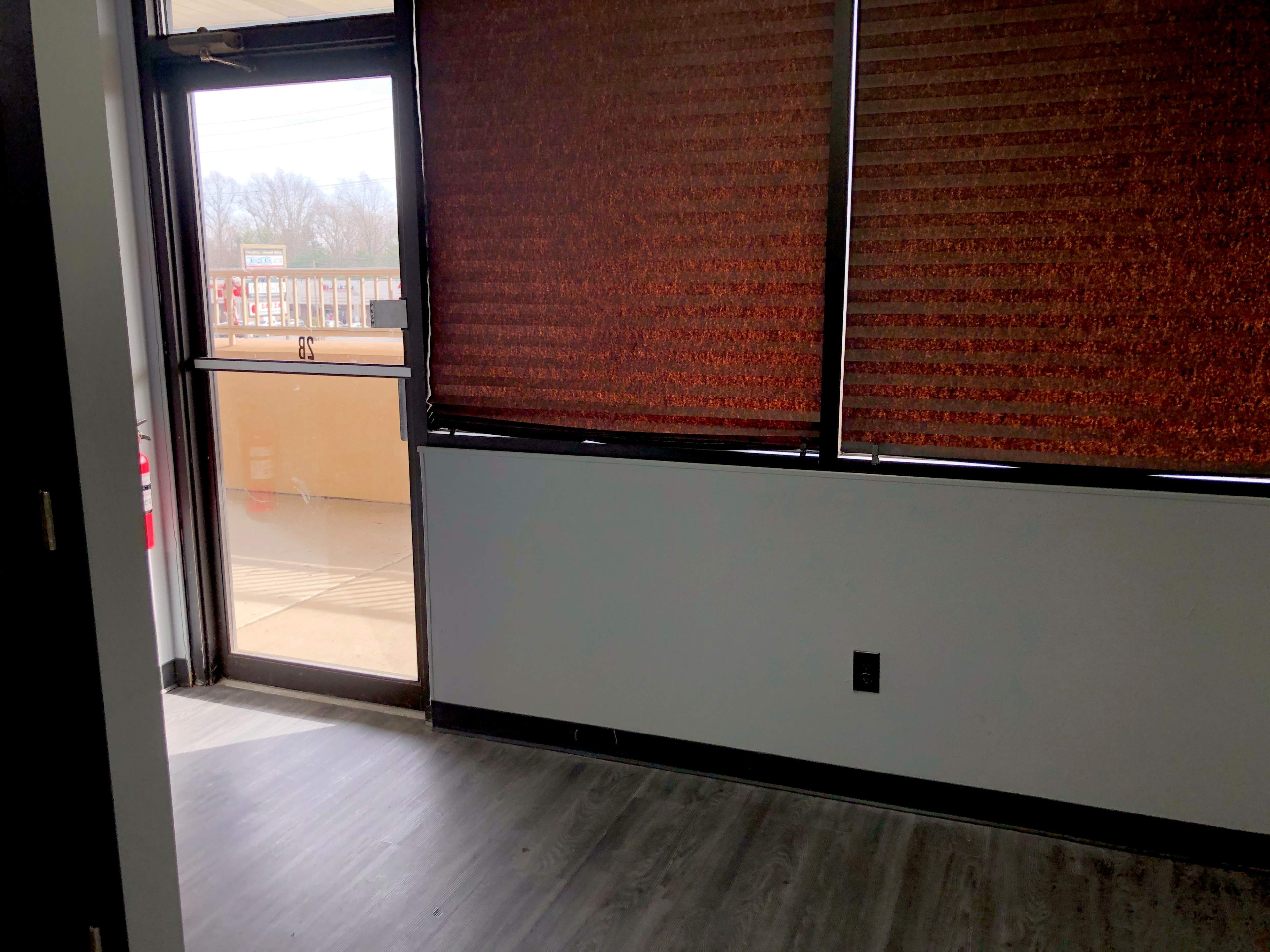 The image shows an empty room with a partially open door and dark window shades.