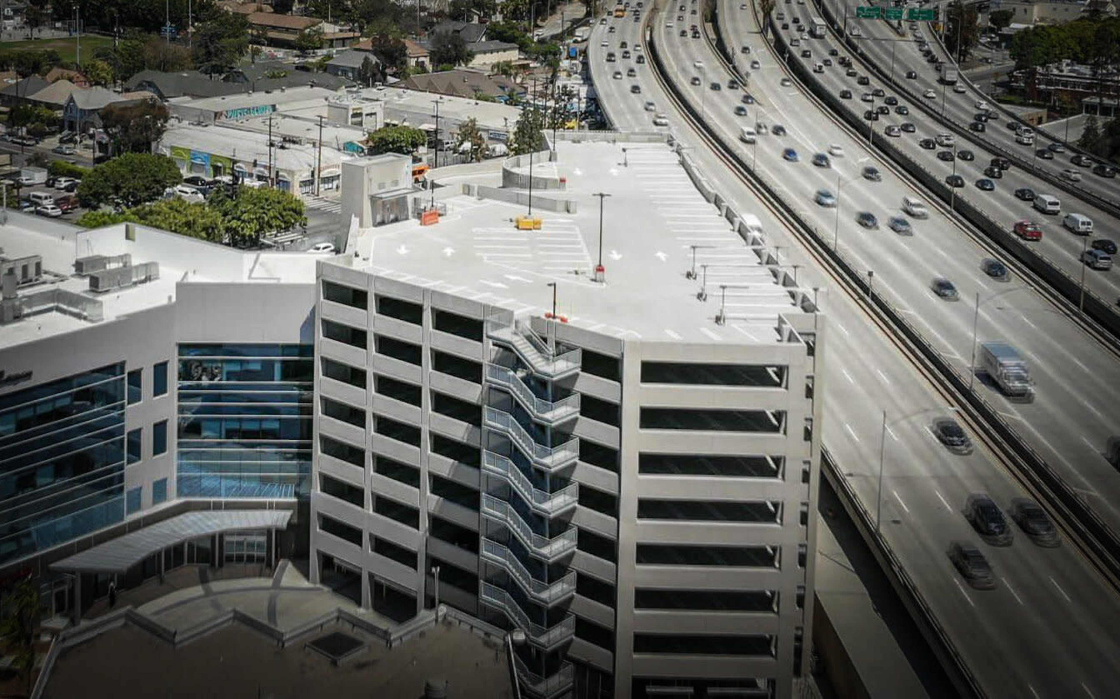 The image shows a multi-story building adjacent to a busy highway, with a parking structure clearly visible.