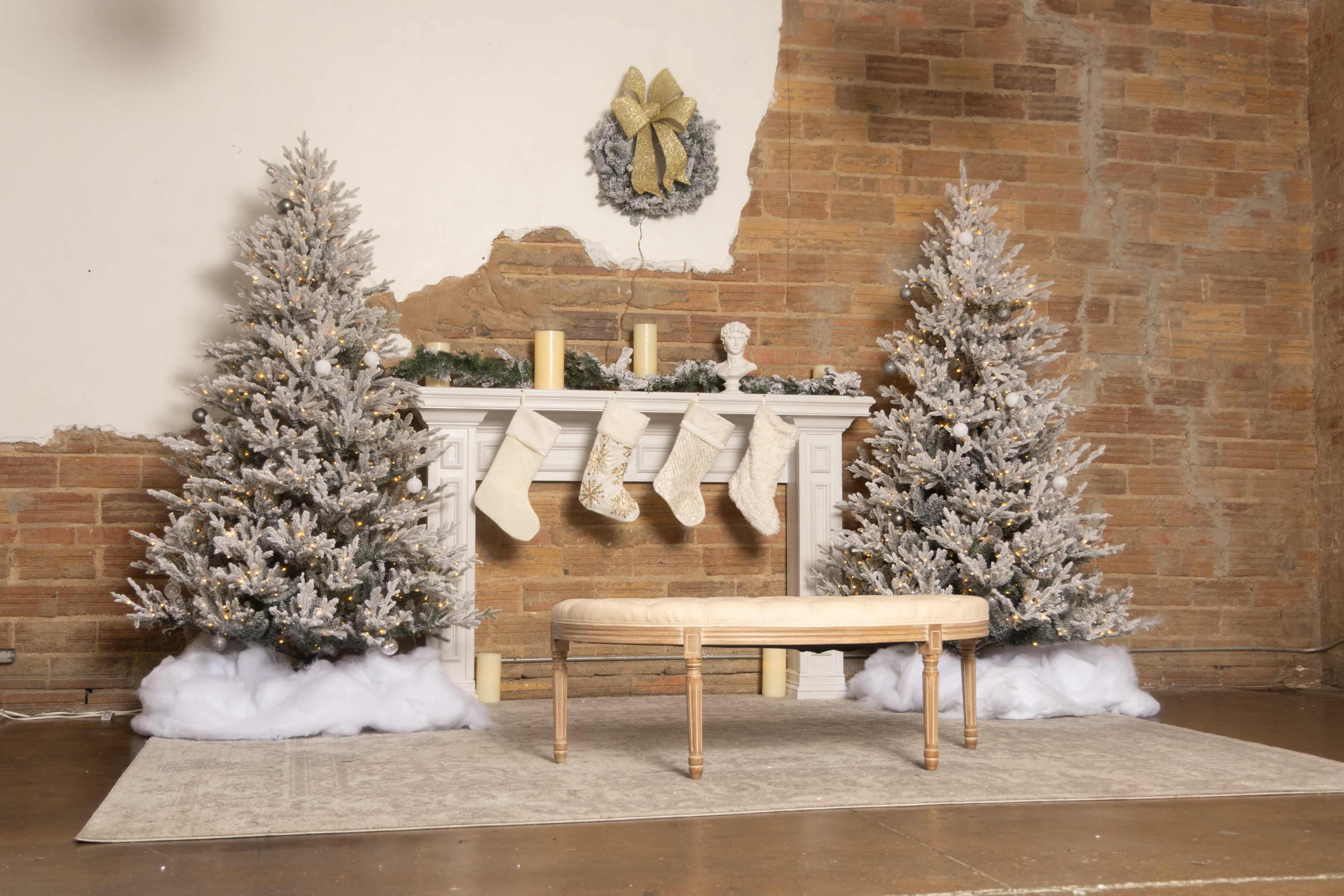 The scene features a decorated mantel with two Christmas trees, stockings hanging above, and a bench placed in front on a rug.