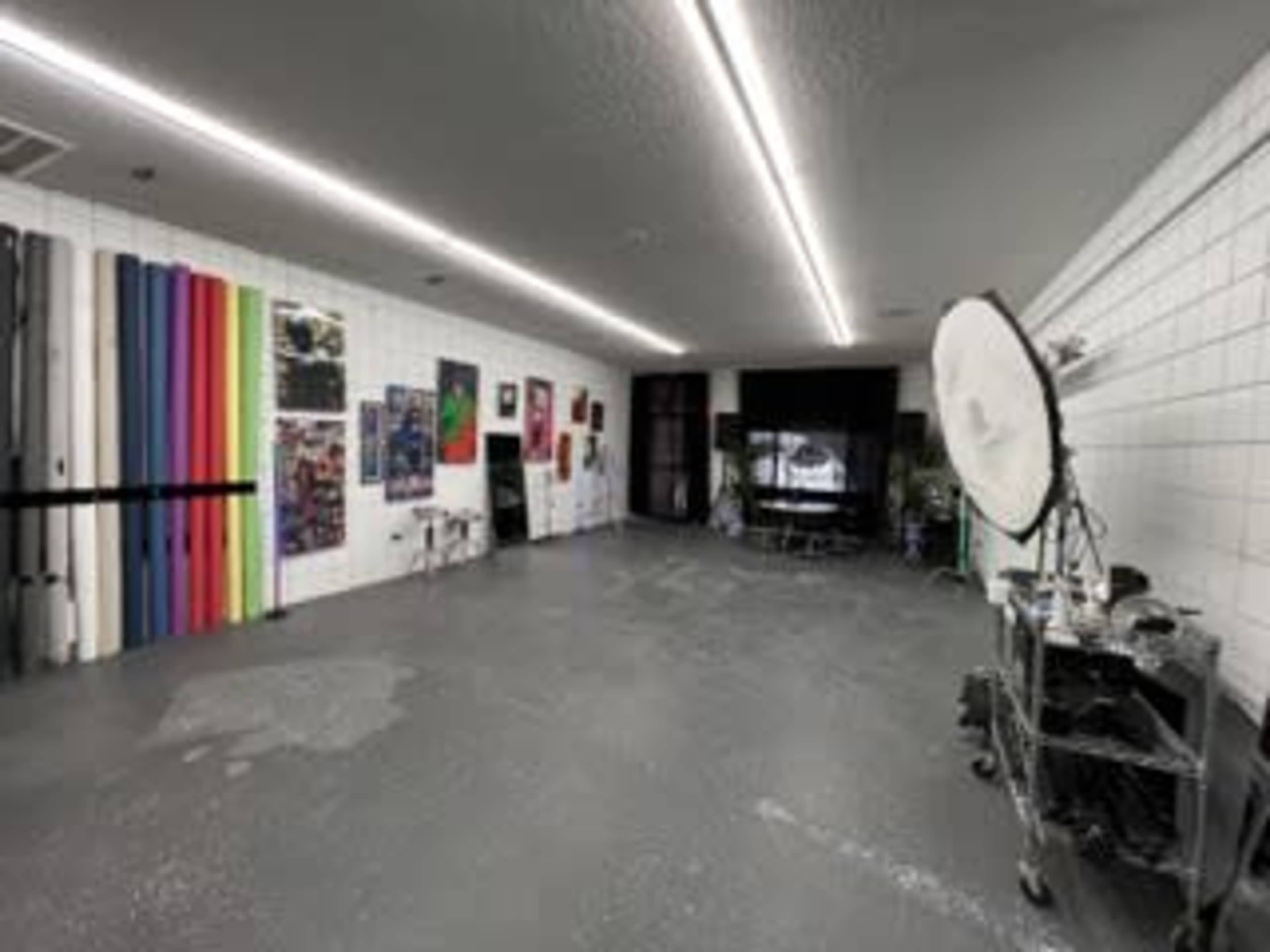 A spacious indoor studio with colorful backdrops on one side and various artworks displayed on the walls.