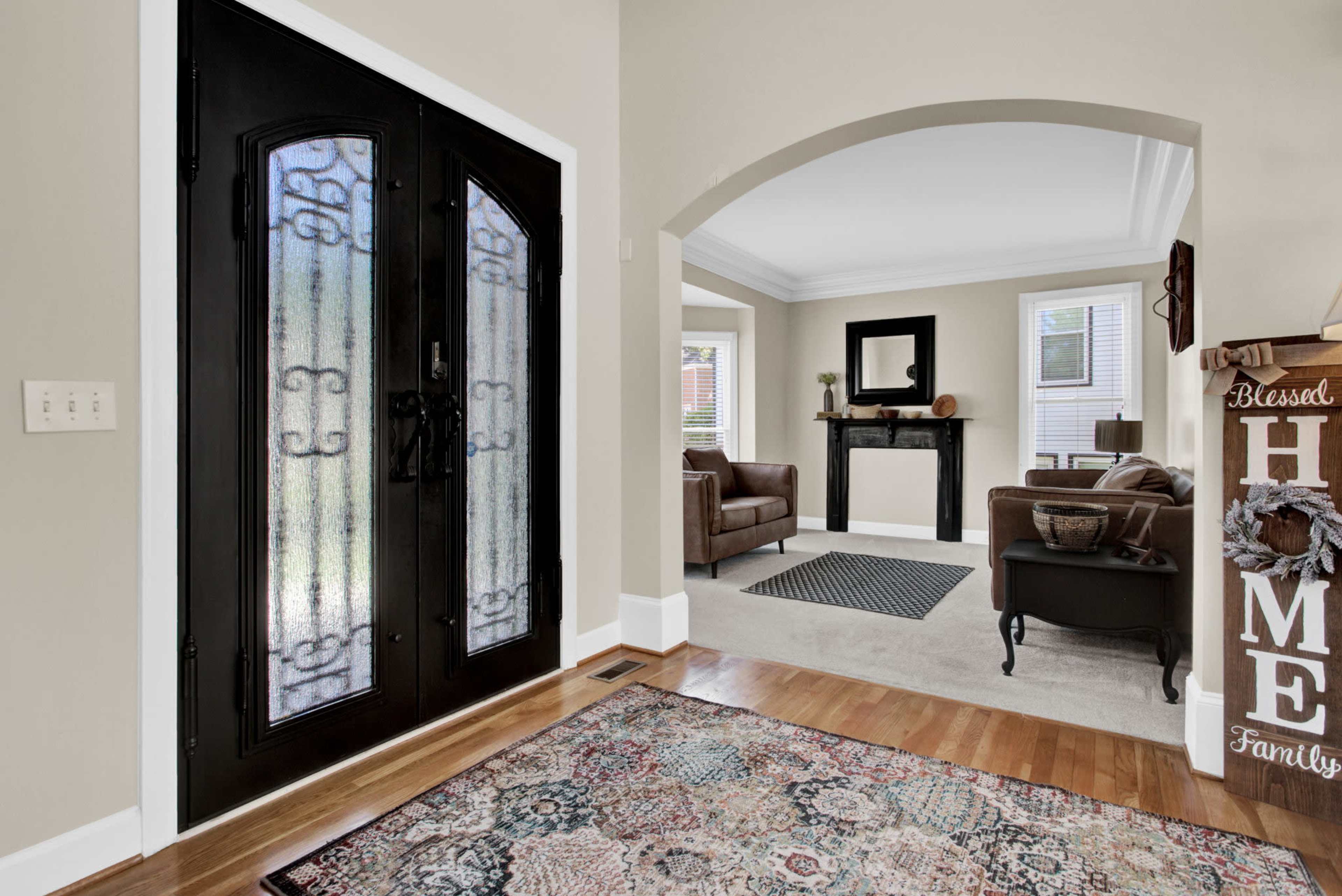 A well-furnished entryway leading to a living room with a fireplace, featuring a patterned area rug and decorative wooden accents.