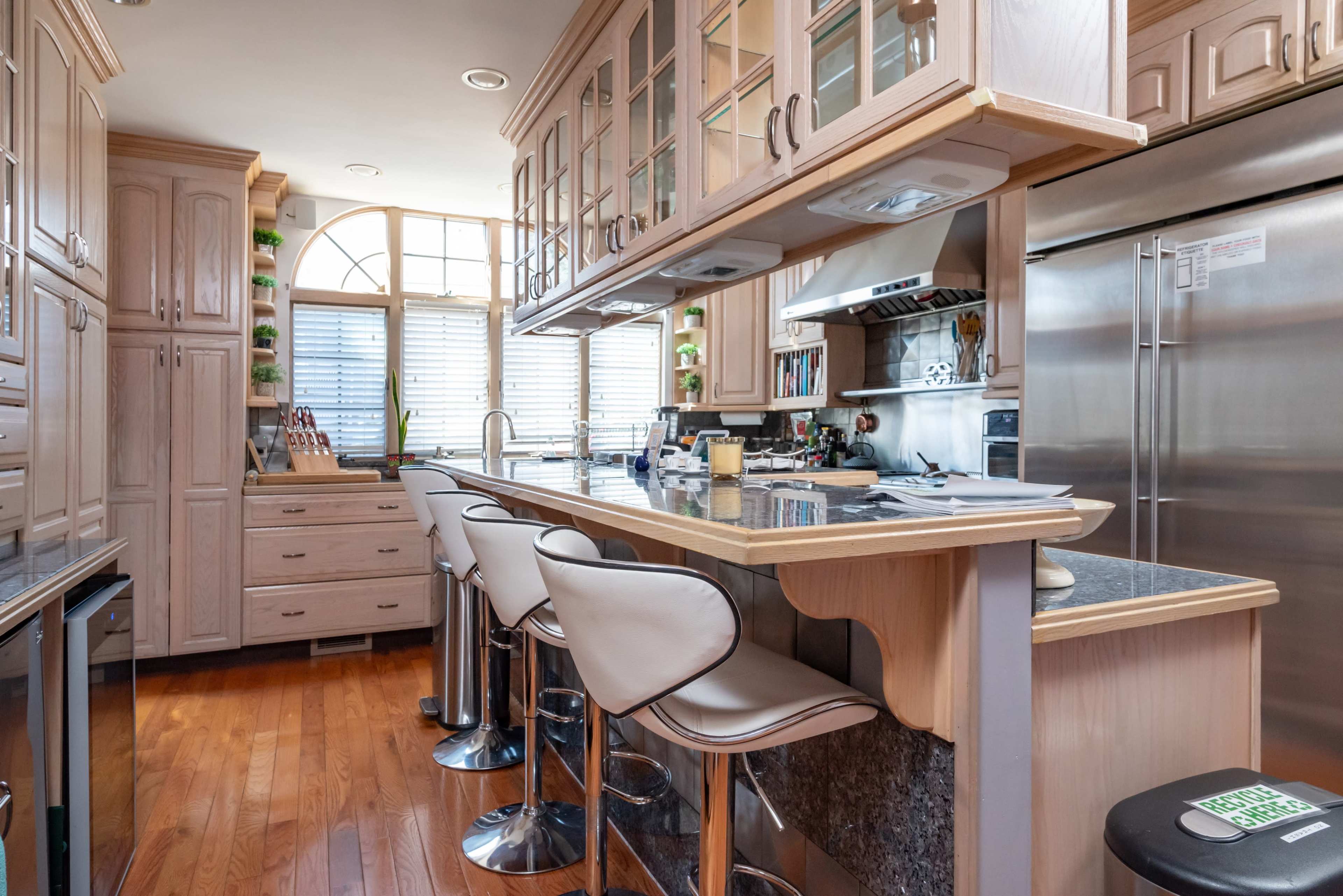 A kitchen with wooden cabinets, a central island with bar stools, and stainless steel appliances.