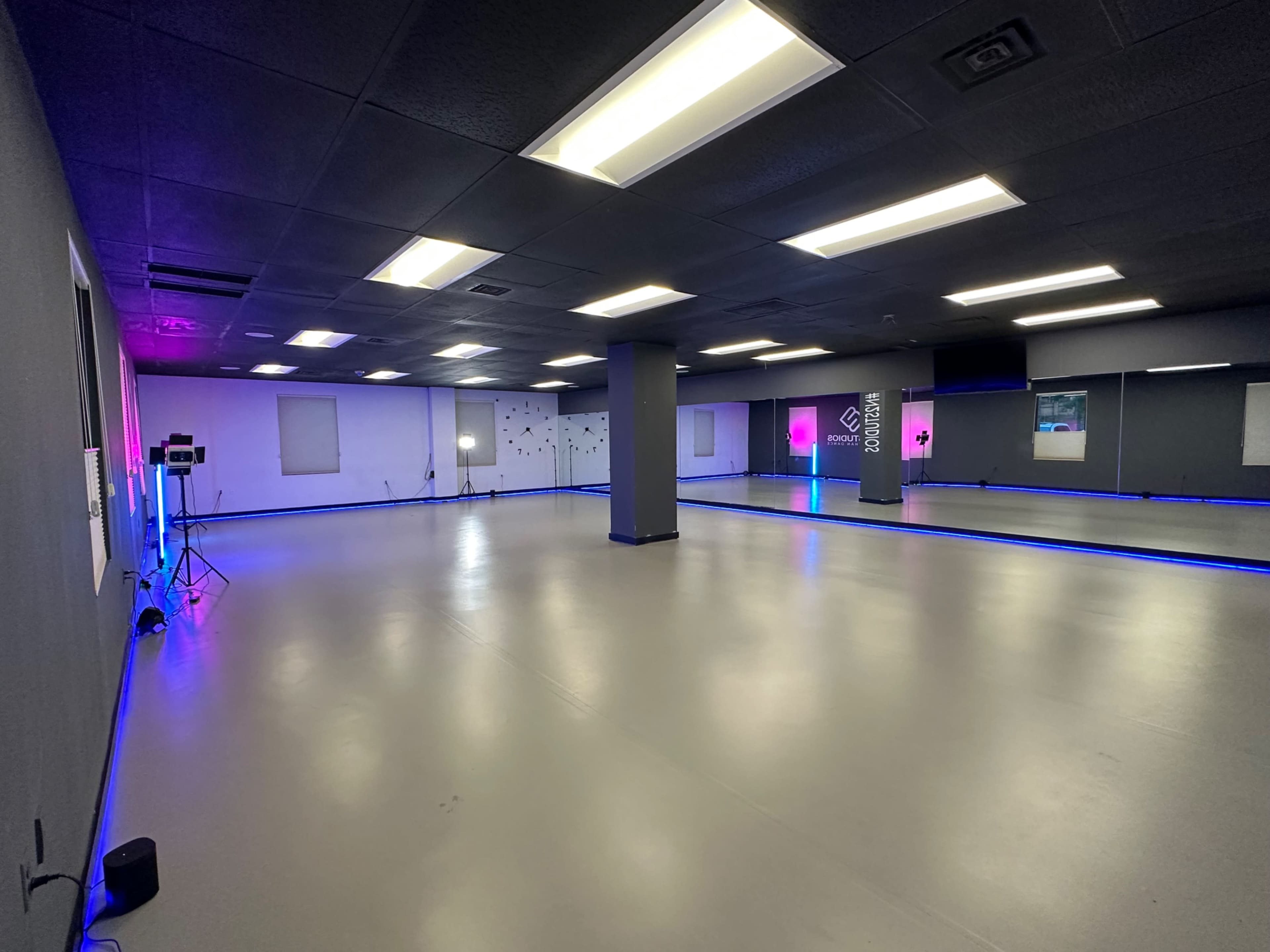 An empty dance studio with colorful LED lighting and a smooth, gray floor.