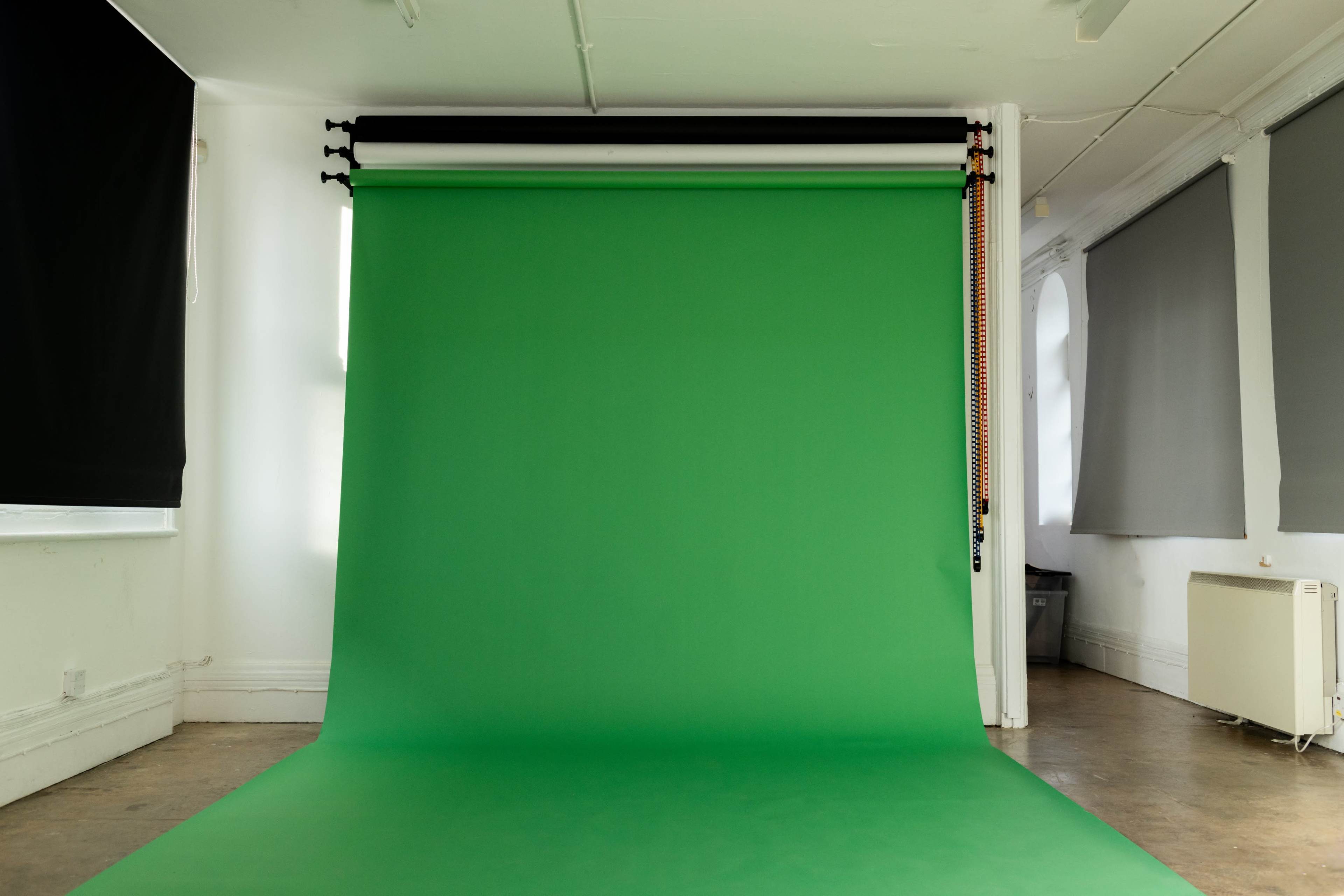 A studio space with a large green backdrop and neutral-colored walls.
