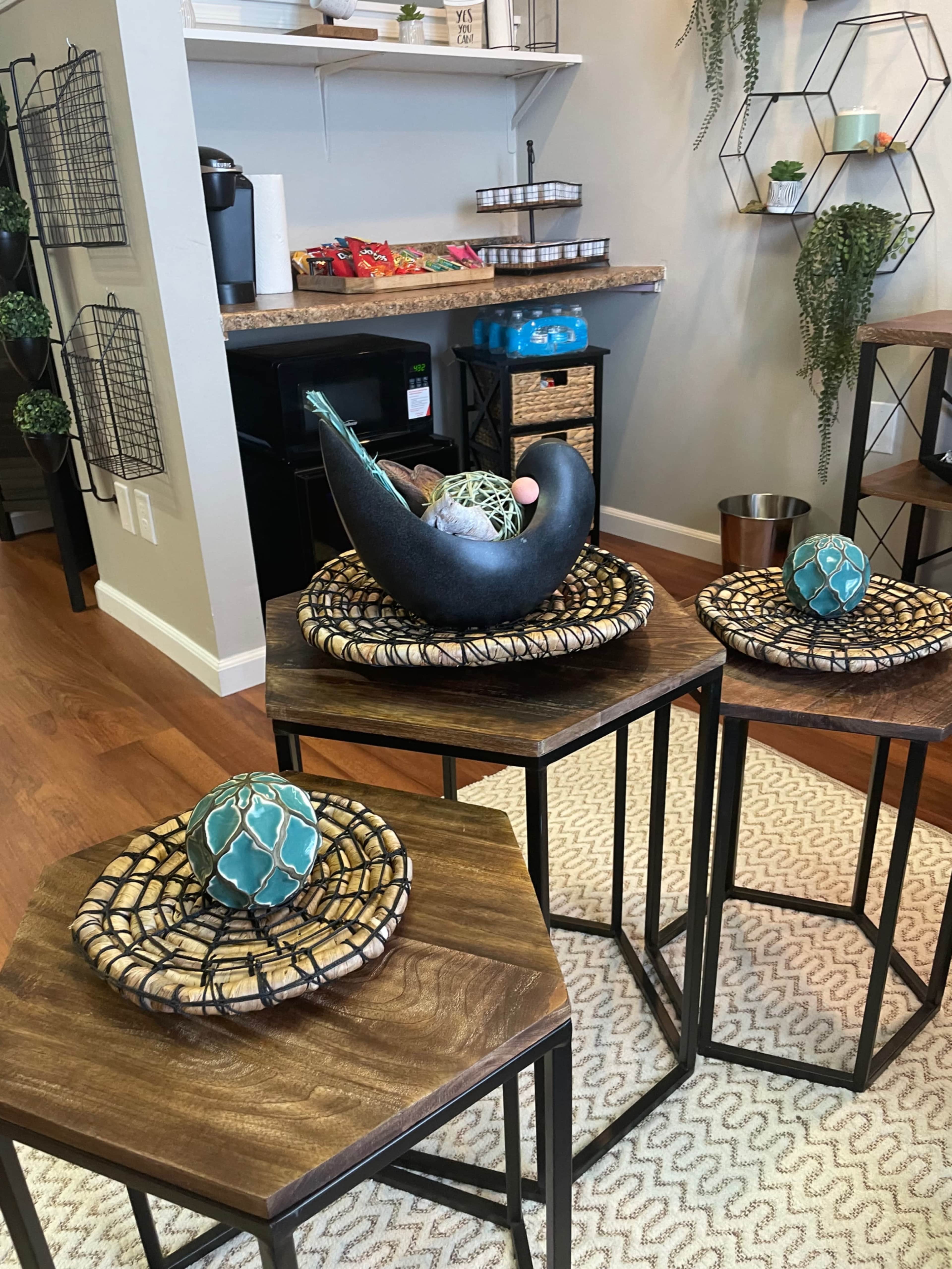 Three wooden nesting tables with decorative bowls and plants are arranged in a modern living space.