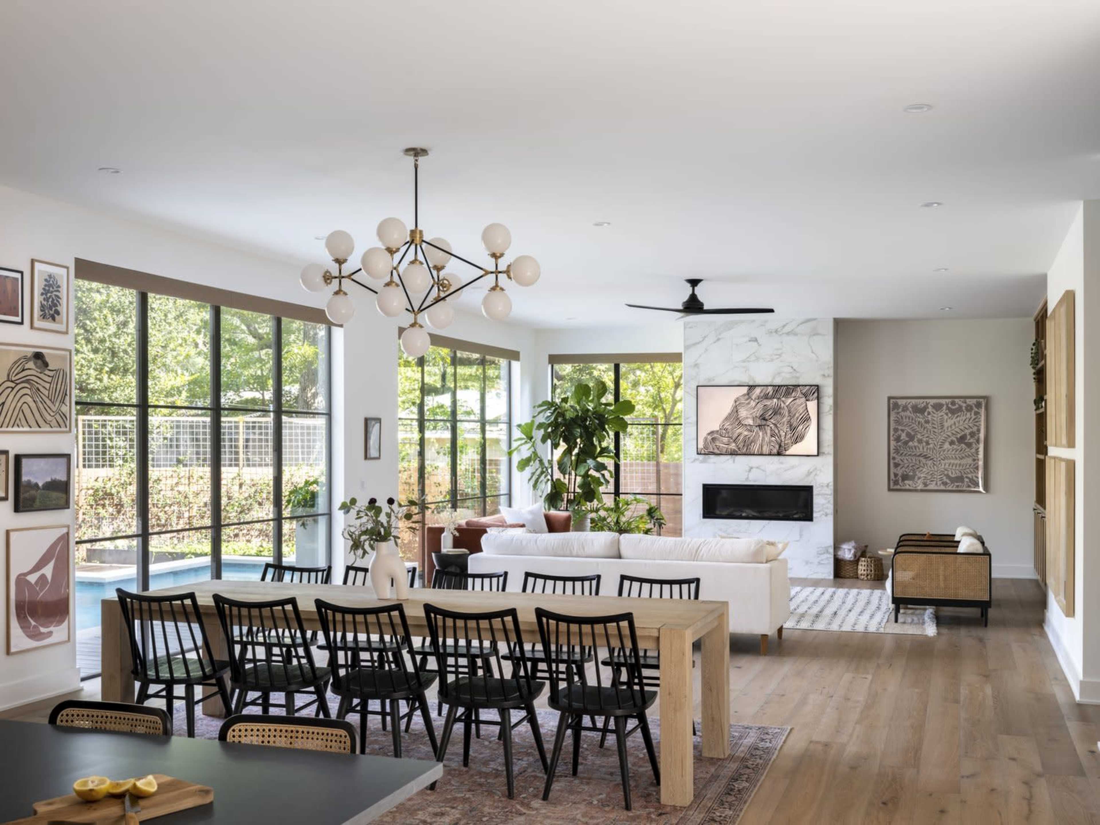 A spacious, modern living area features a white sofa, dining table, and large windows overlooking a patio.