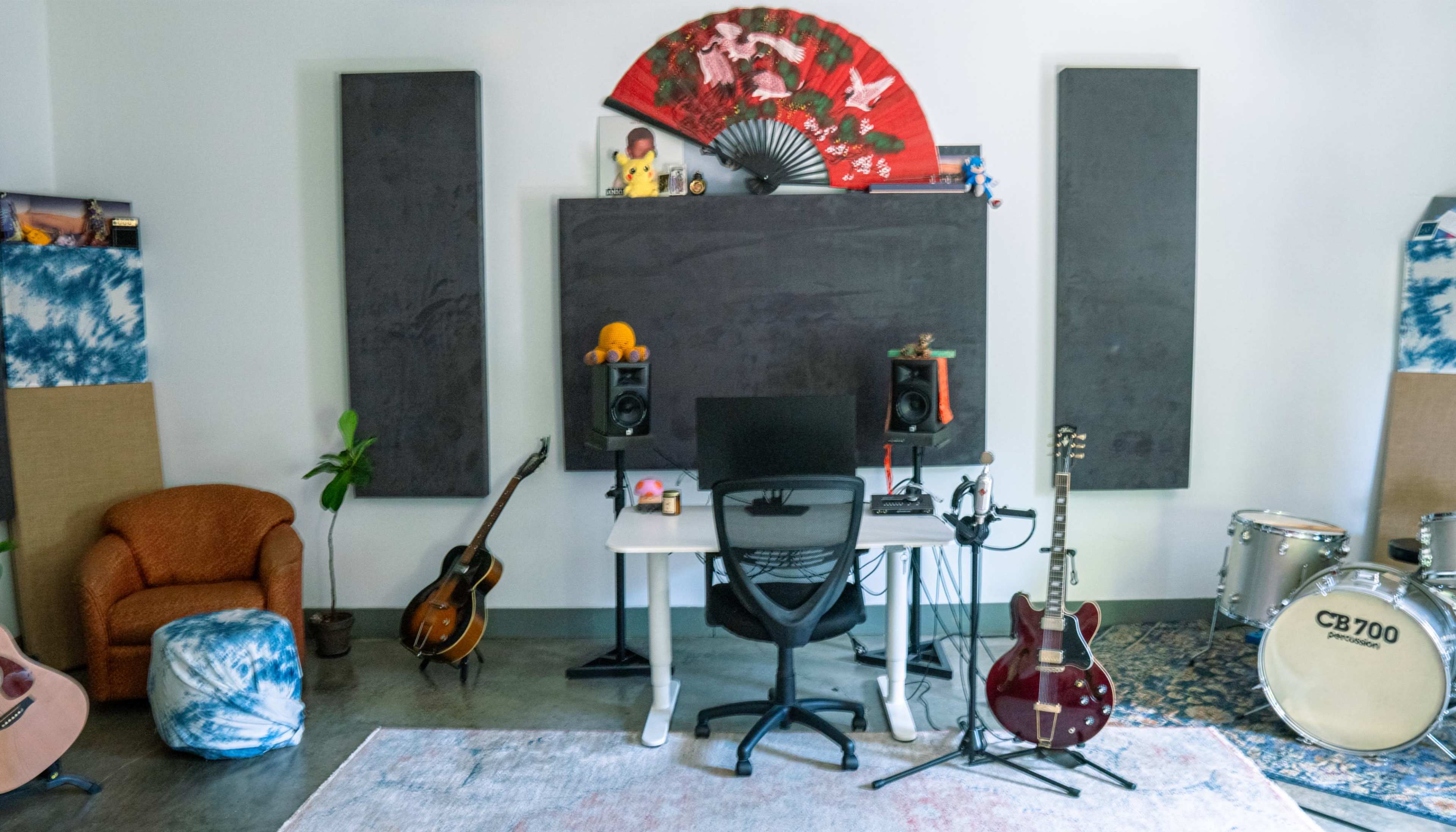 The image shows a_music studio featuring a desk with a chair, various musical instruments, a large blackboard, and decorative wall elements.