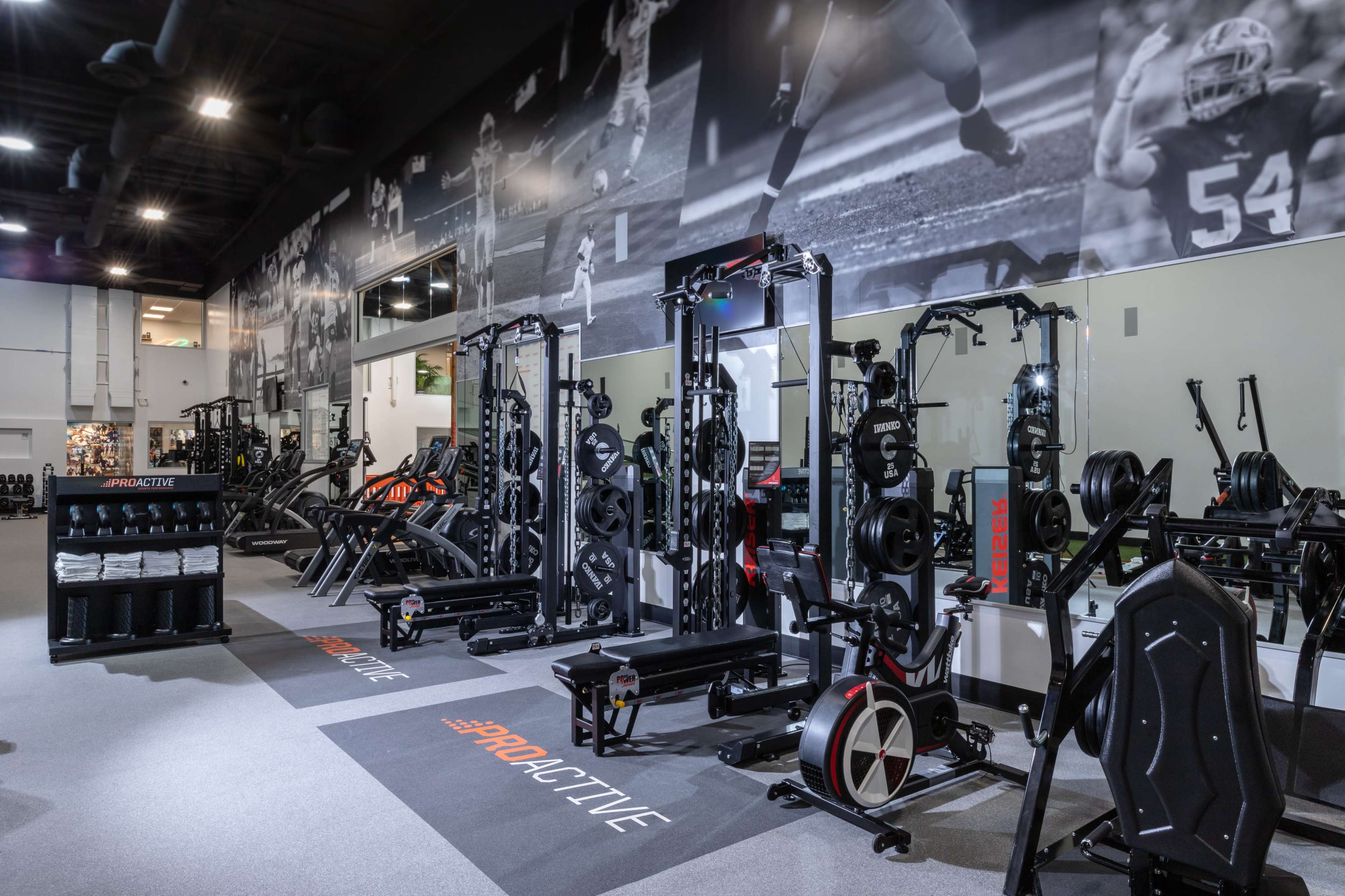 The image shows a fitness center equipped with a variety of gym machines and workout stations arranged neatly along the walls.
