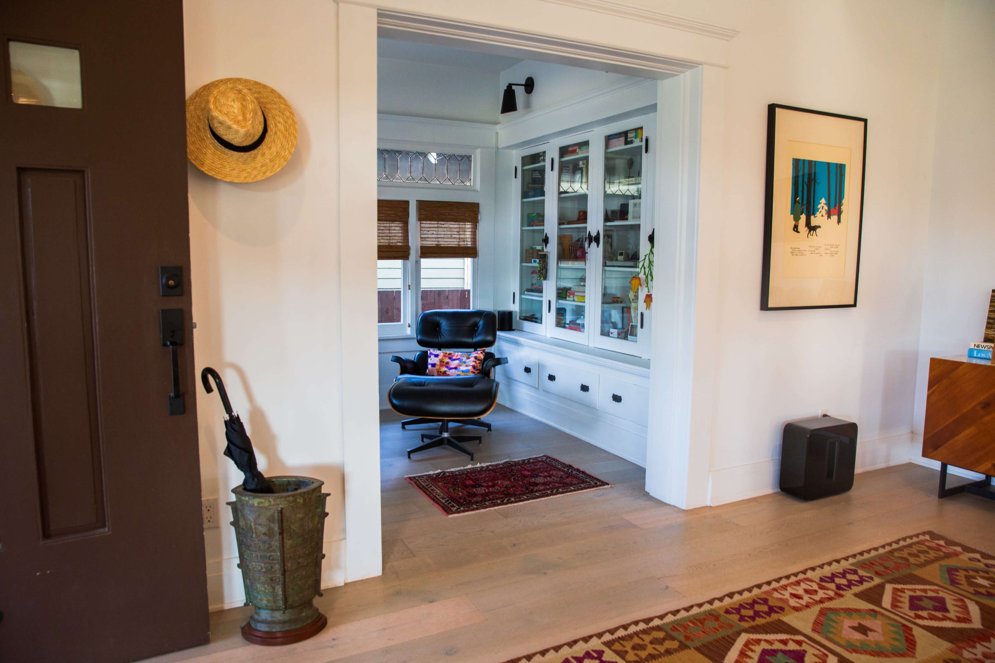 The image shows a cozy interior featuring a doorway leading to a small sitting area with a black chair and a glass-fronted cabinet filled with decorative items.